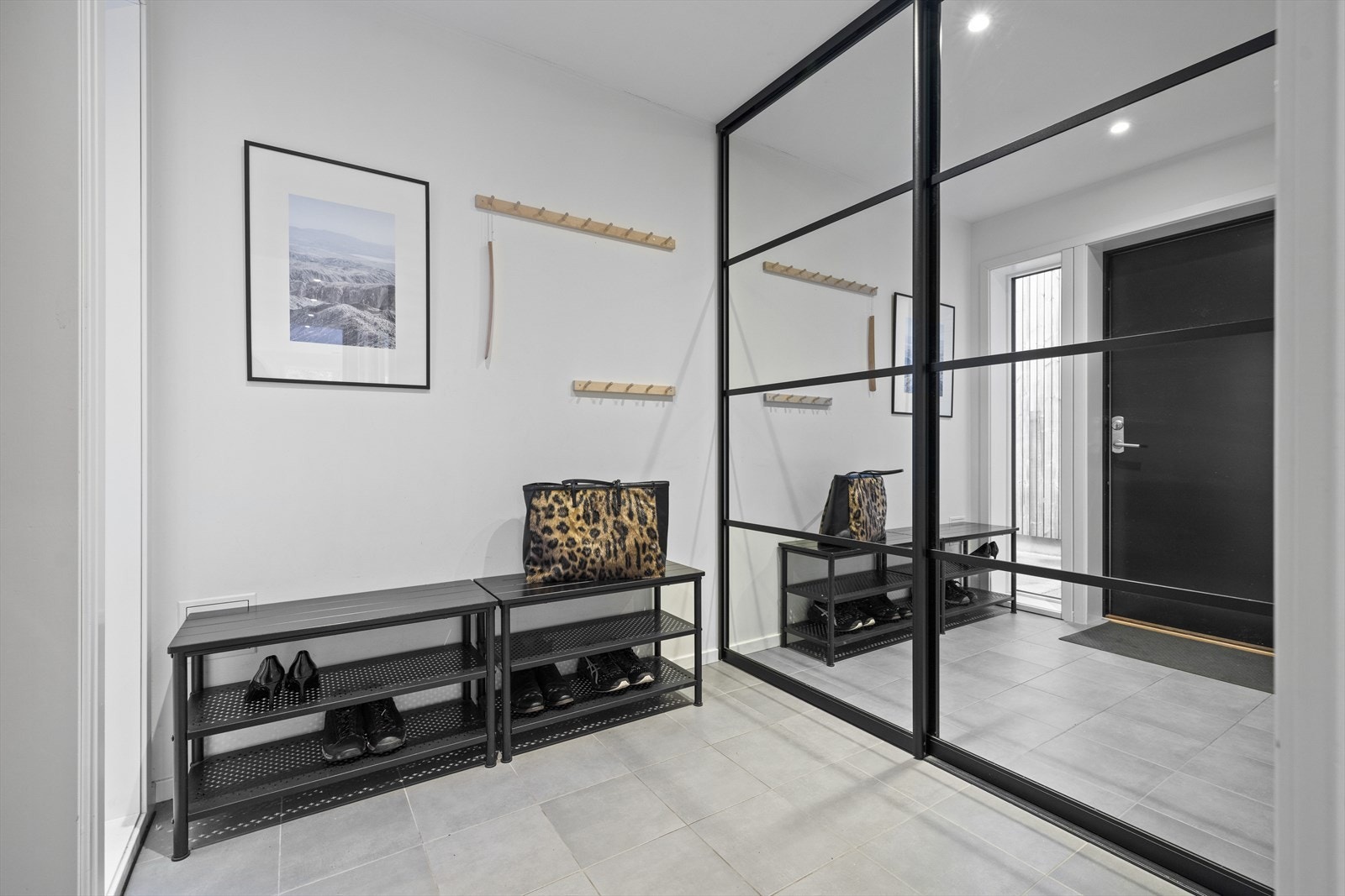 Romslig entré med flislagt gulv over gulvvarme. Veggene og himlingen er malt i lyse, delikate farger. Praktisk speil skyvedørsgarderobe med rikelig oppbevaringsplass Galleribilde