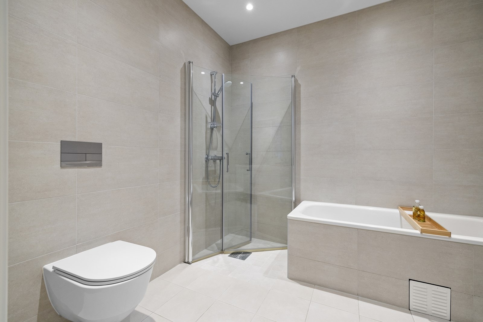 Badet er innredet med nedfelt servant, veggmontert toalett, dusjvegger/hjørne og innbygget badekar Galleribilde