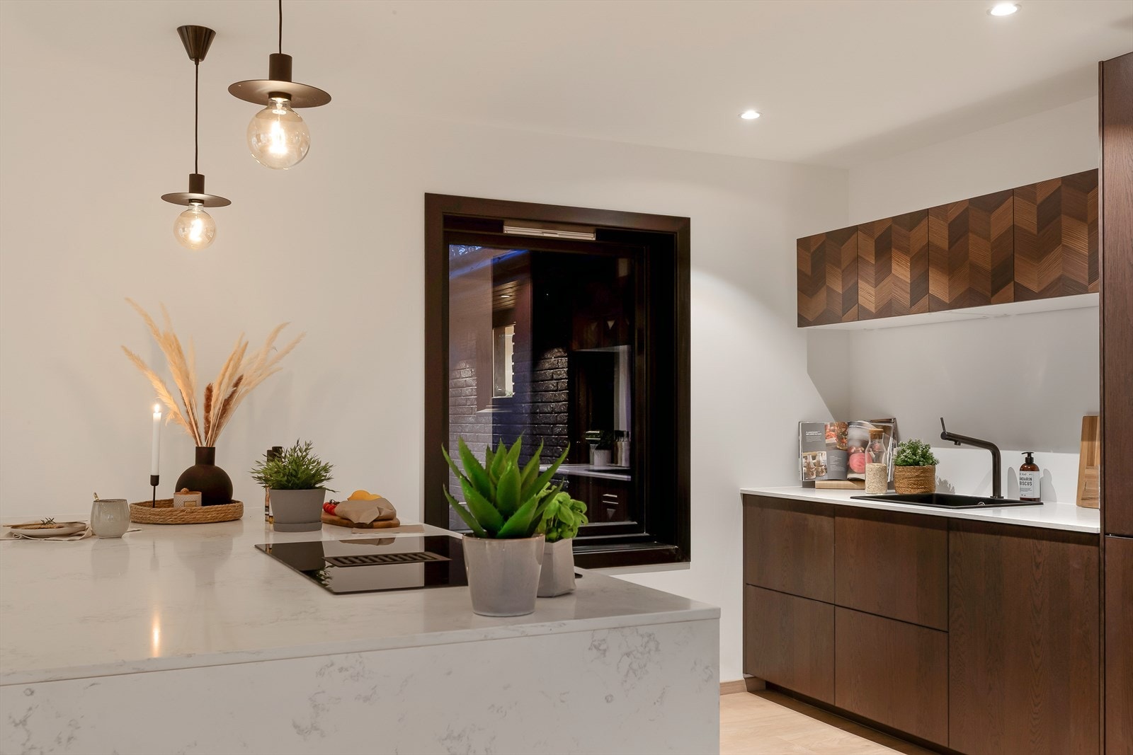 Det flotte kjøkkenet fra 2022 har en stilren utforming med innredning i over- og underskap på én side og en stor, praktisk kjøkkenhalvøy. Galleribilde