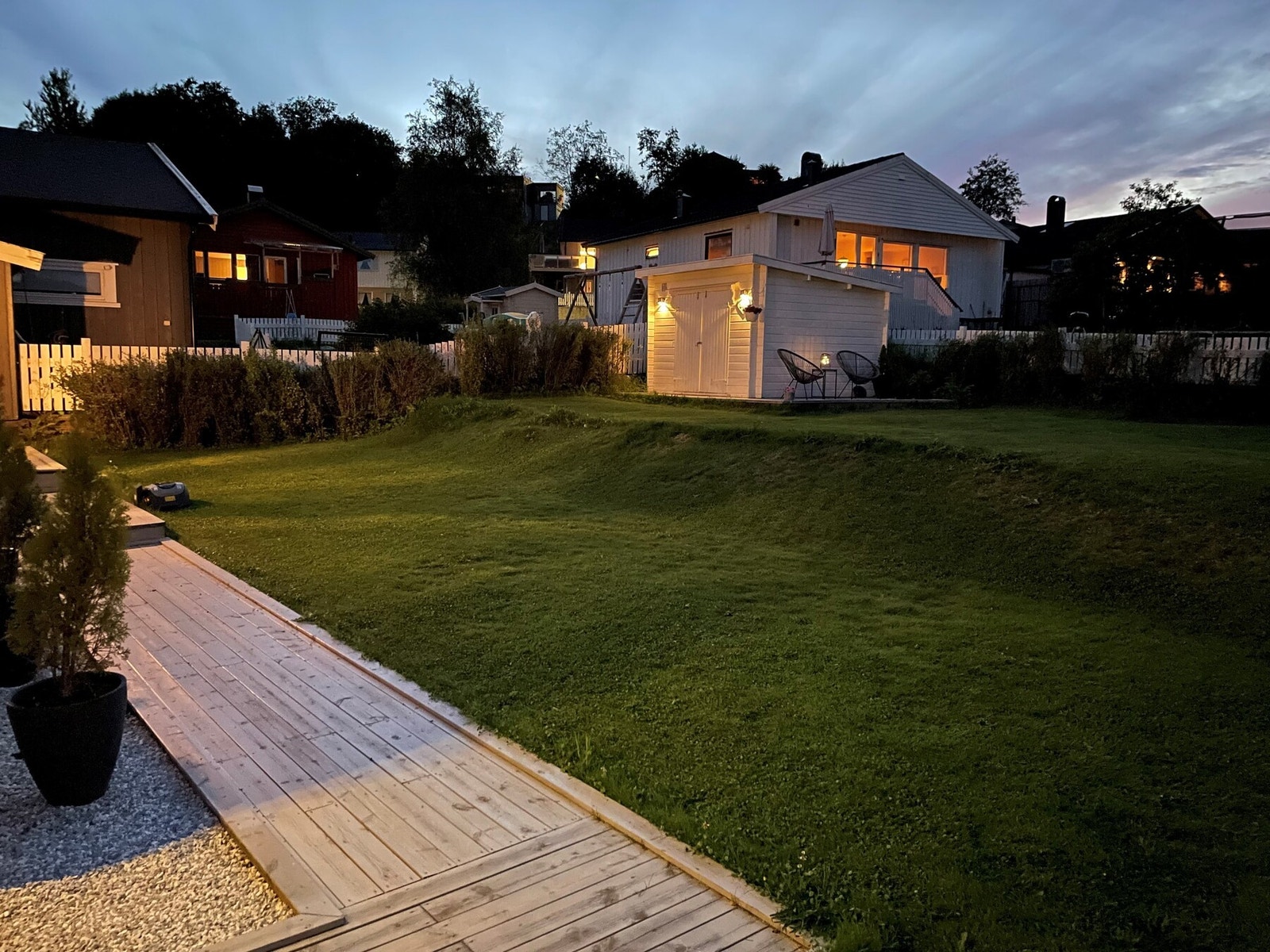 Stemningsfull uteplass med opplyst bod og vakker beplantning - perfekt for lune sommerkvelder. Galleribilde