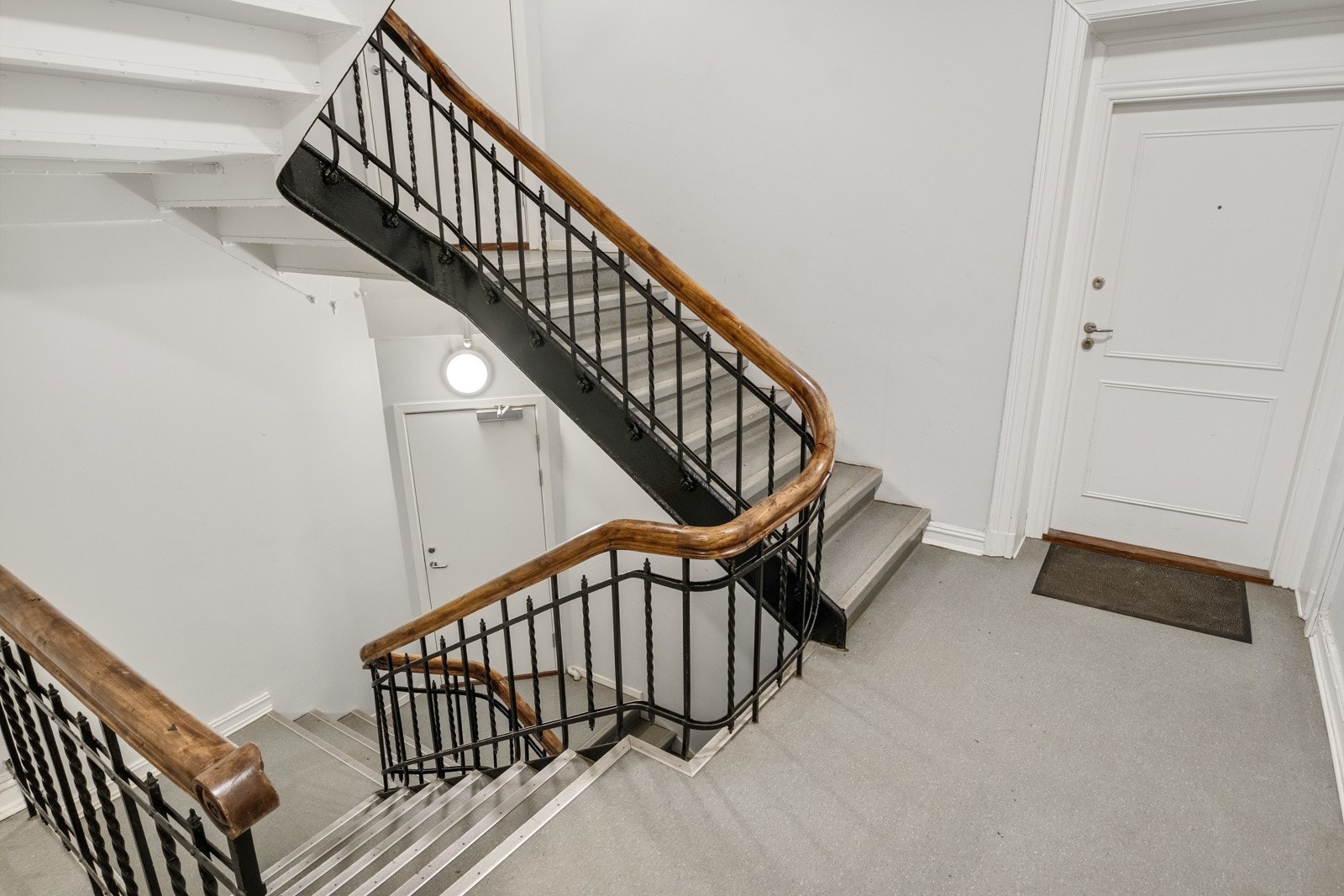 Boligen har enkel adkomst i annen etasje. Inngangsdøren til boligen er til høyre i bildet, og dør til bod i trappeløpet midt i bildet. Galleribilde