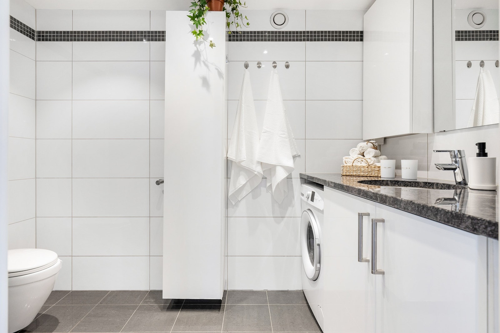 Badet er pent flislagt på gulv og vegger med elektrisk gulvvarme og har flere praktiske løsninger. Galleribilde