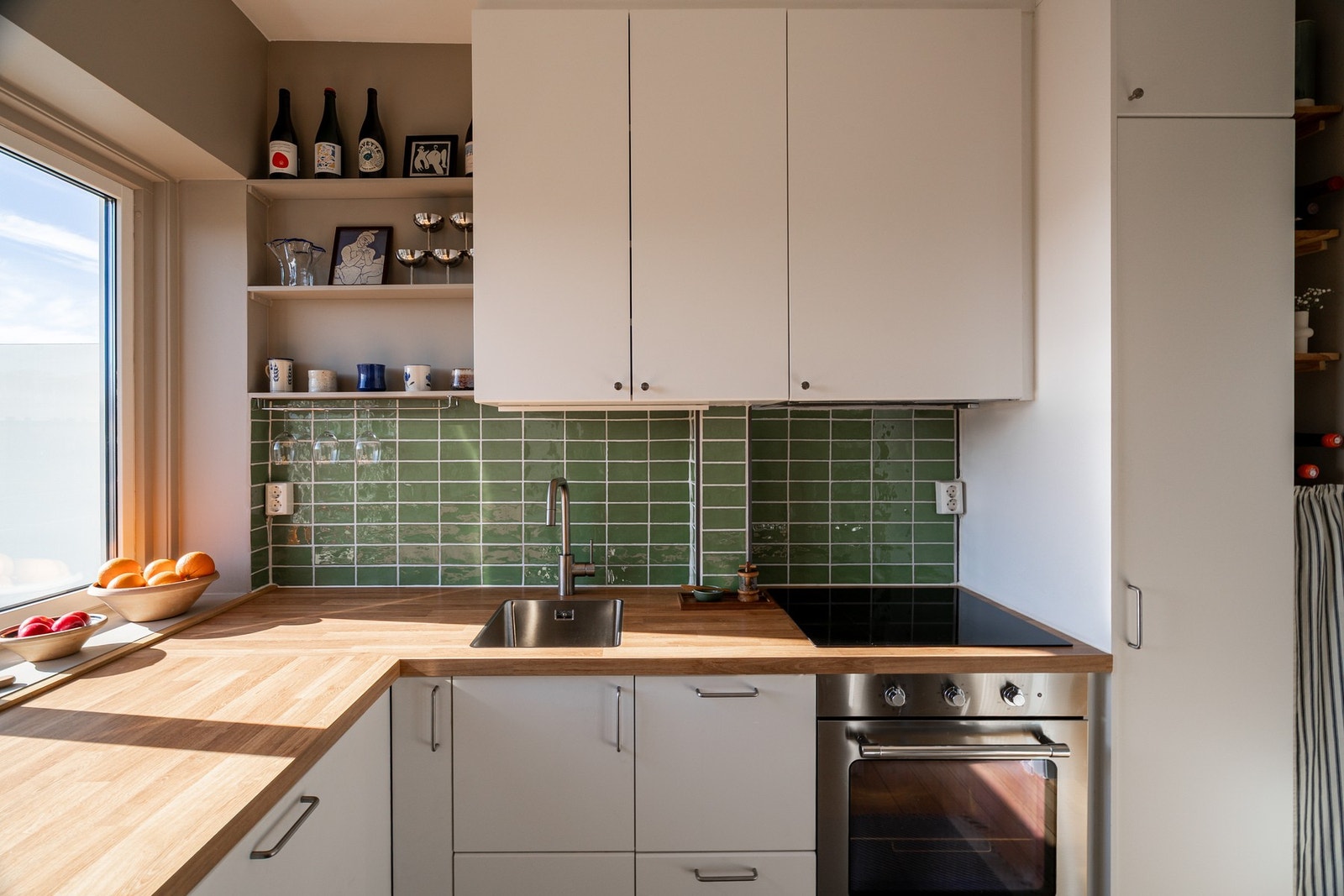 Lys kjøkkeninnredning med hvite slette fronter, benkeplate og nedsenket oppvaskkum Galleribilde