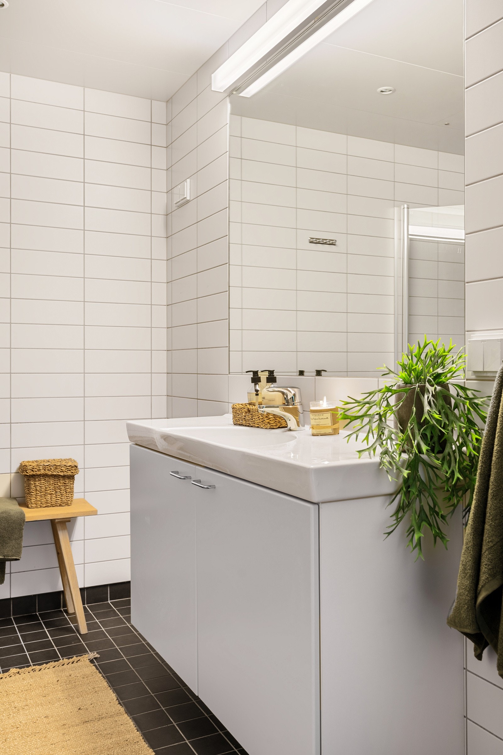 Badet er innredet med servant med underskap, speil med belysning, vegghengt toalett, dusjhjørne med foldbare glassdører og opplegg for vaskemaskin. Galleribilde