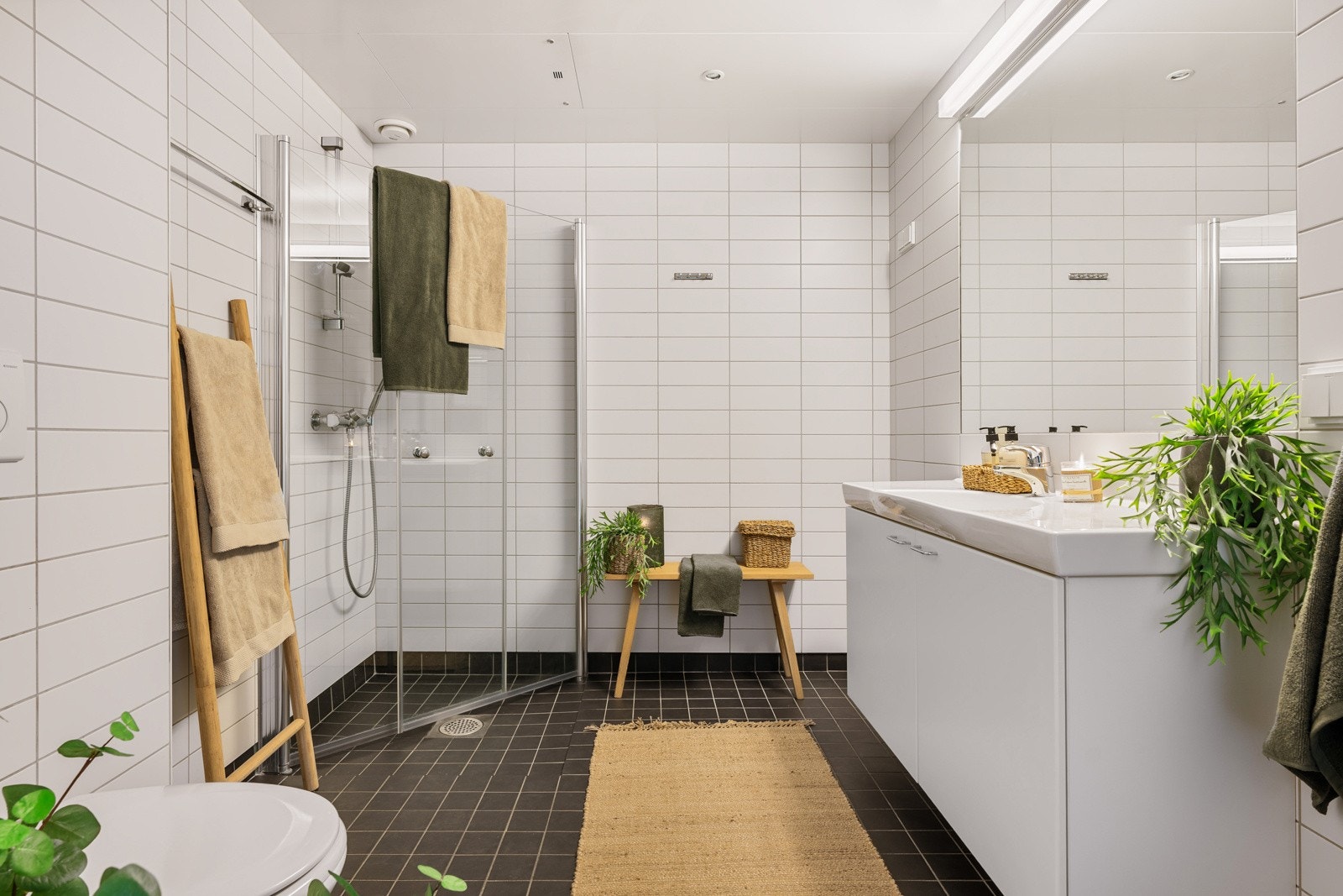 Hovedbadet er plassert sentralt i leiligheten og måler 5,9 kvm. Badet har et stilrent design med mørke gulvfliser kombinert med lyse veggfliser. Galleribilde