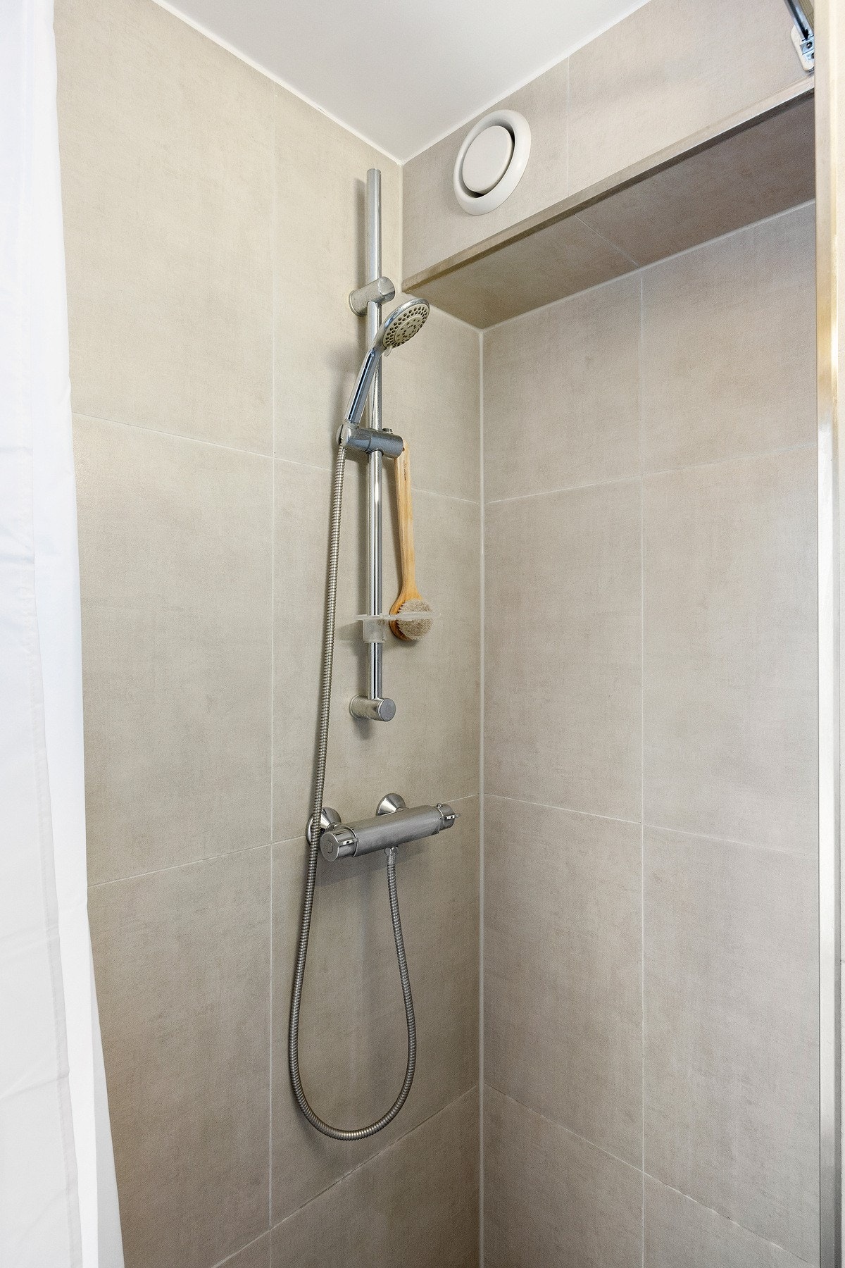 Badet er innredet med toalett, speil, servant med innredning og dusjhjørne med forheng. Galleribilde
