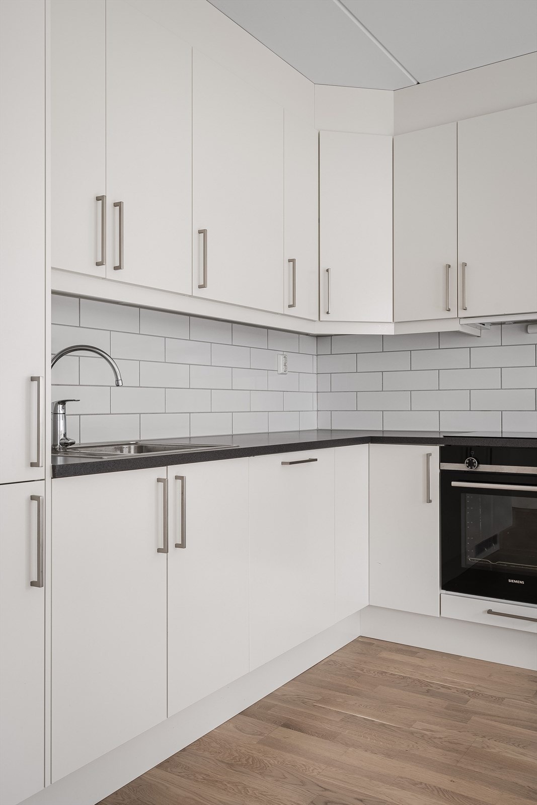 Det er lyse fliser i benkerygg og lys under overskap. Innredningen har integrert kjøl- og frys, oppvaskmaskin, stekeovn og kjøkkenventilator. Galleribilde