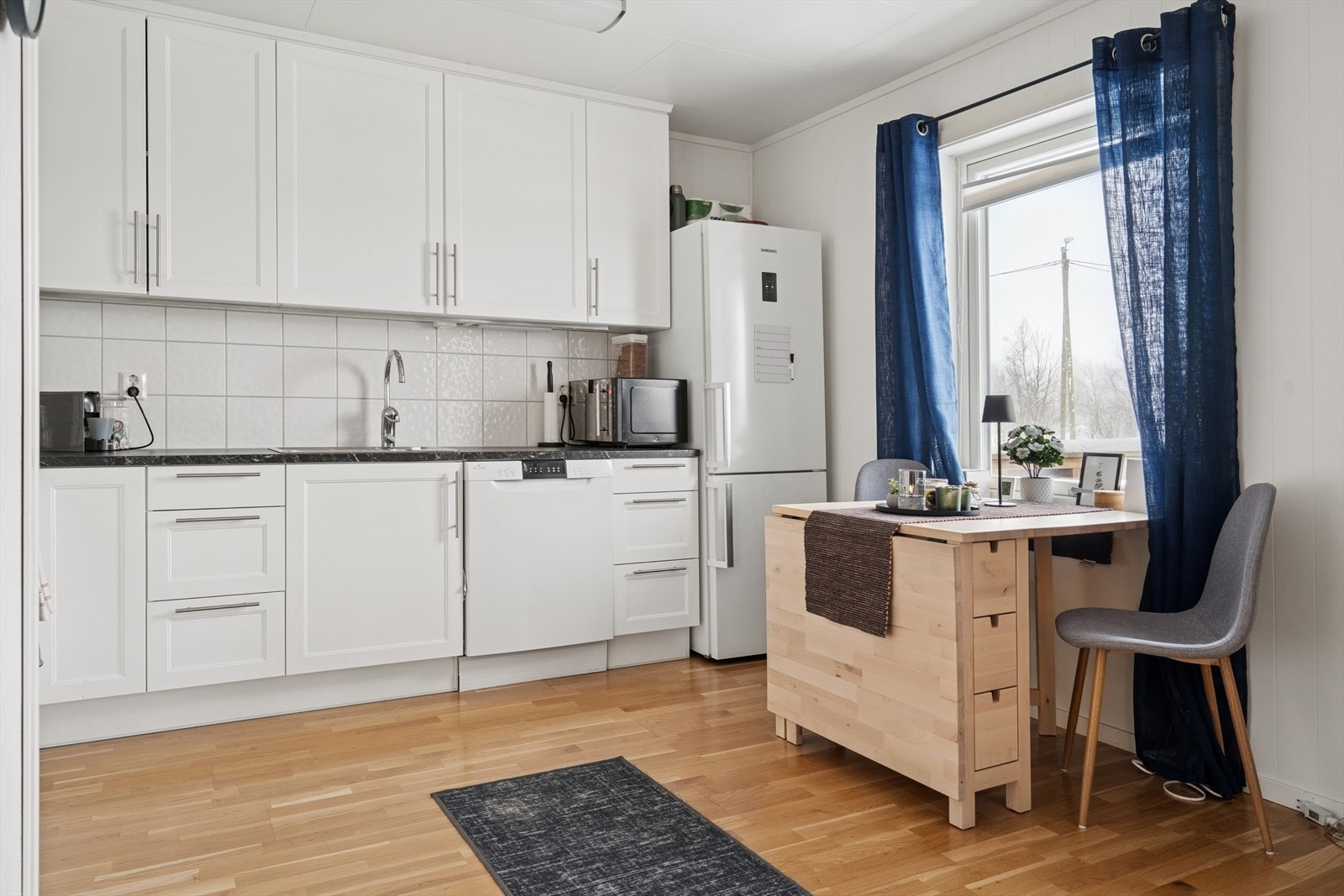 Kjøkkenet er utstyrt med frittstående hvitevarer, inkludert kjøl-/fryseskap, komfyr og oppvaskmaskin Galleribilde