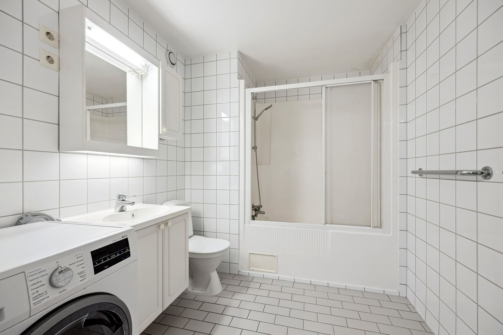 Flislagt baderom med opplegg for vaskemaskin. Galleribilde
