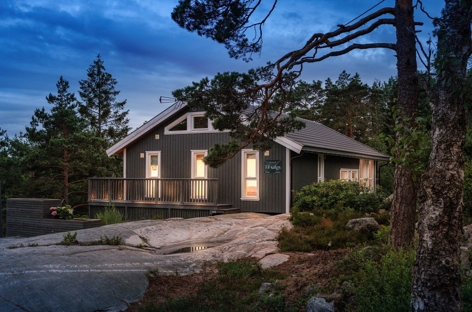 Helårshytta fra 2017 har dypt saltak og mørkmalt panel med hvite karmer Galleribilde