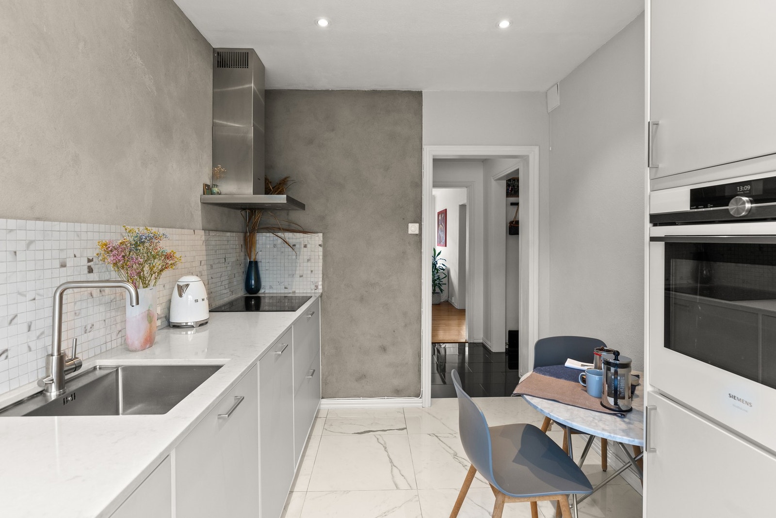 Kjøkkeninnredning fra "Kvik" utstyrt med eksklusiv kompositt benkeplate, mosaikkfliser, slette fronter, og integrerte hvitevarer Galleribilde