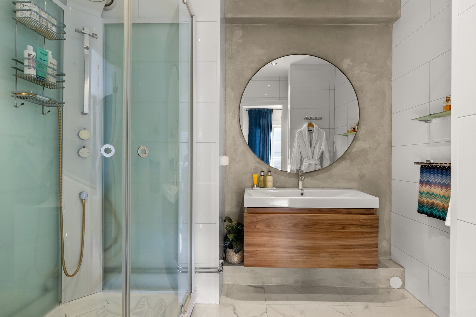 Flislagt baderom med varmekabler innredet med nedfelt servant, dusjkabinett og opplegg for vaskemaskin Galleribilde