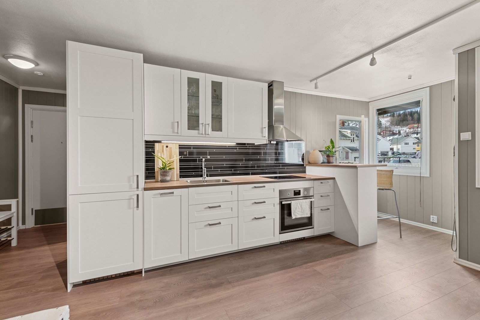 Her er det en stilfull kjøkkeninnredning fra 2018, utført med hvite, profilerte fronter og laminert benkeplate med kjøkkenkum. Galleribilde