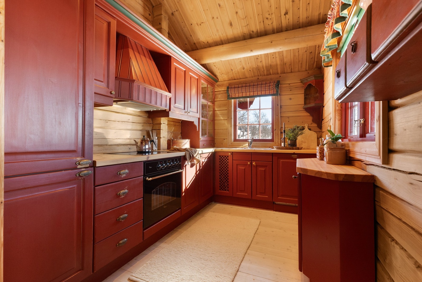 Kjøkken med innredning av heltre, malt i en flott rødfarge som kler hytta godt Galleribilde