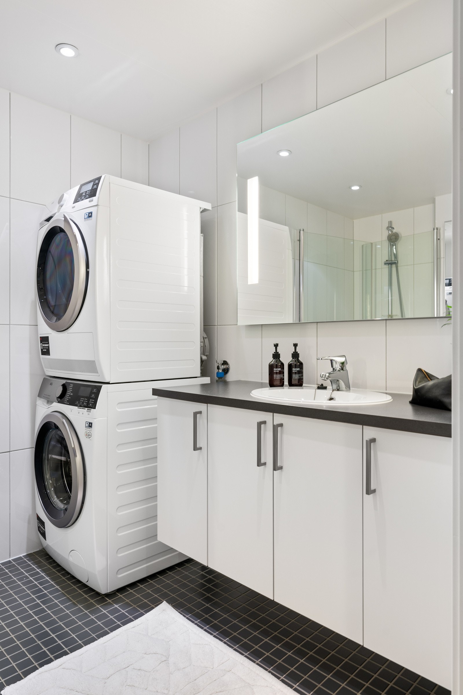 Bader er utstyrt med en romslig baderomsinnredning, opplegg for vaskemaskin, dusjhjørne med innfellbare dører, vegghengt toalett og speilflate. Galleribilde