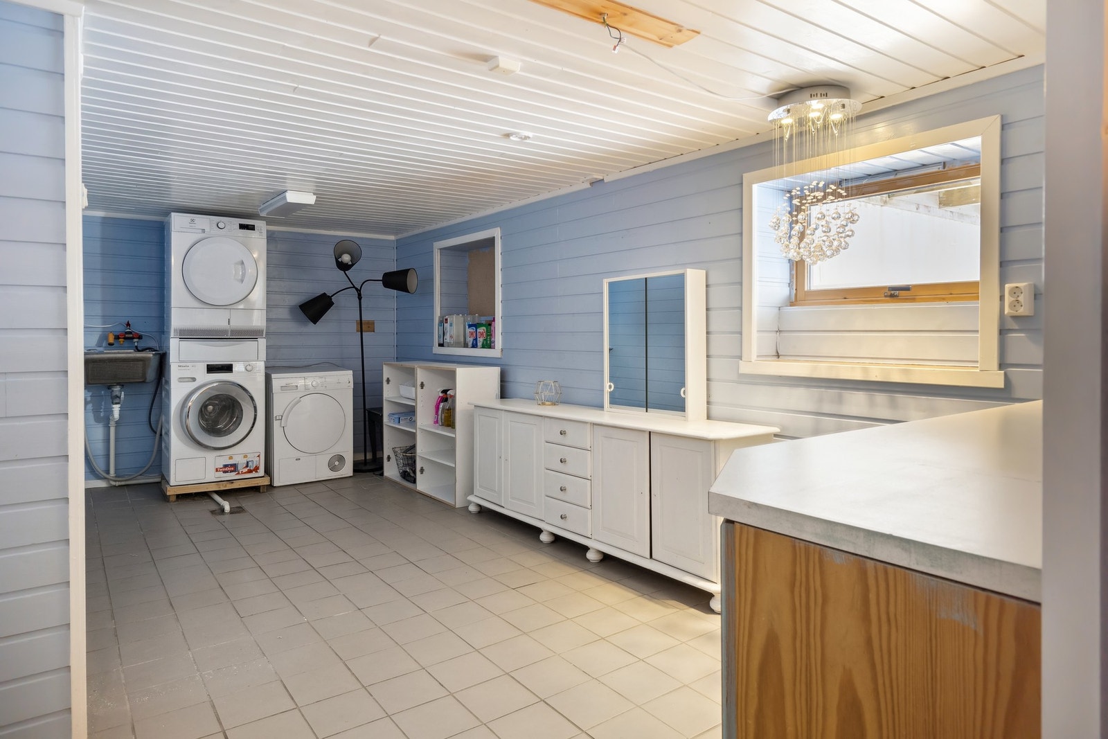 Praktisk og romslig vaskerom. Vegger og tak kledd i malt panel, flis på gulv. Galleribilde