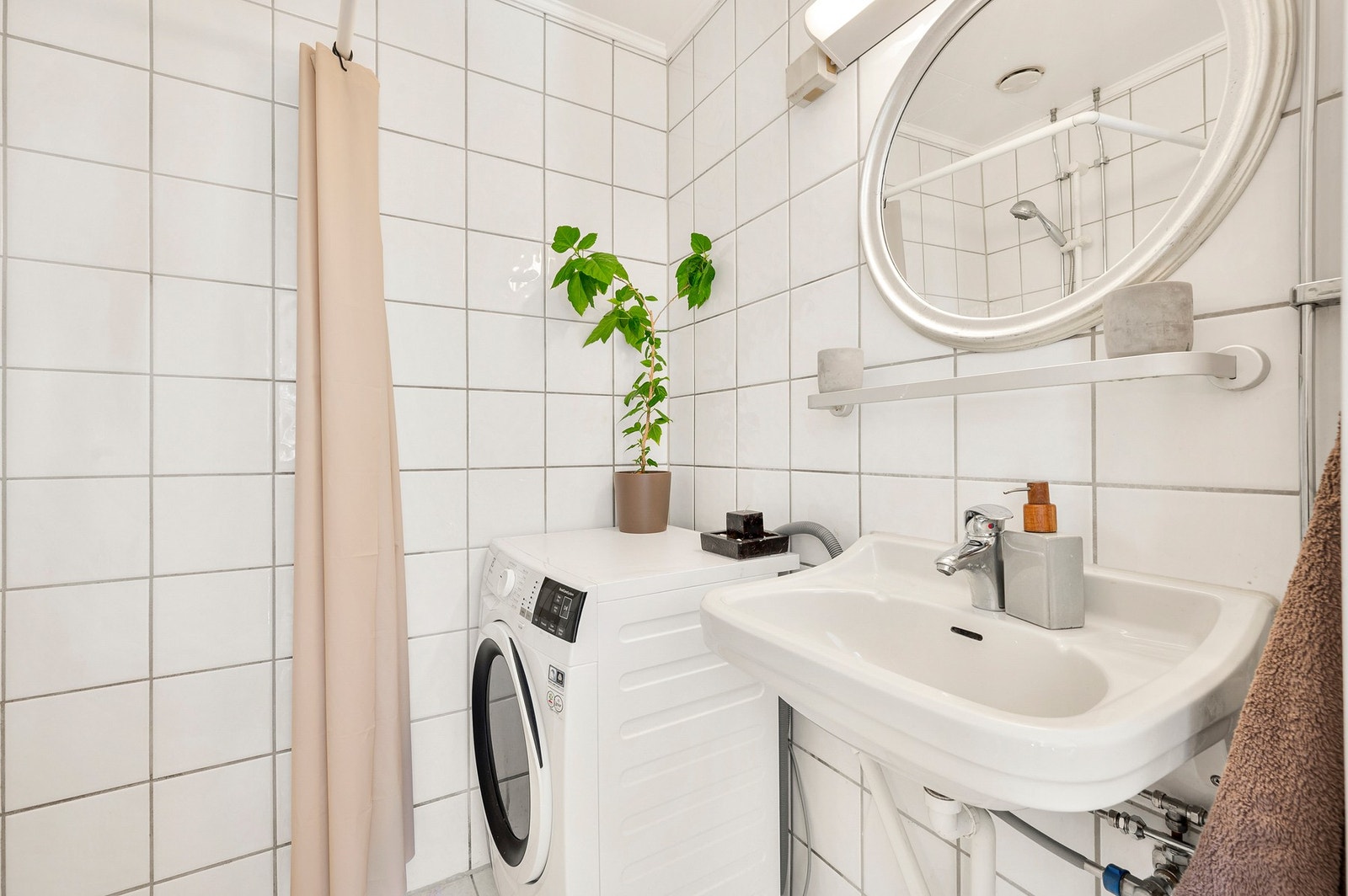 Lyst, flislagt bad med opplegg for vaskemaskin. Galleribilde