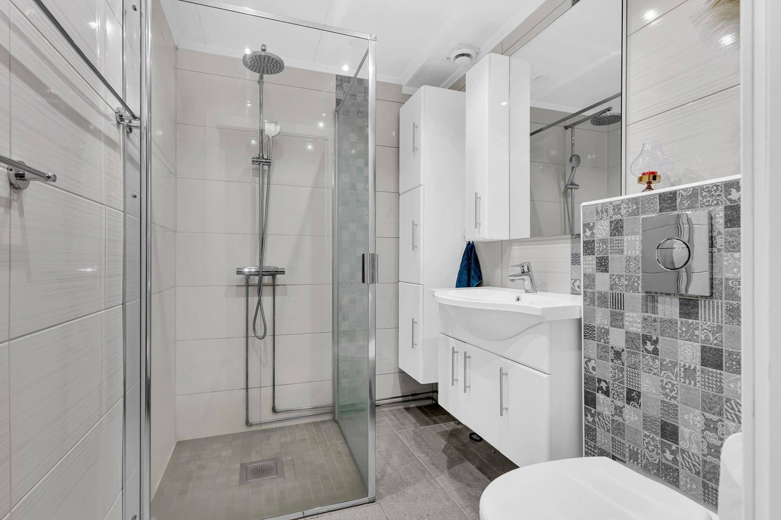 Det moderne badet består av servantskap med 1-greps blandebatteri og underskap. Vegghengt toalett og dusjhjørne med glassdører. Elektrisk gulvvarme. Galleribilde