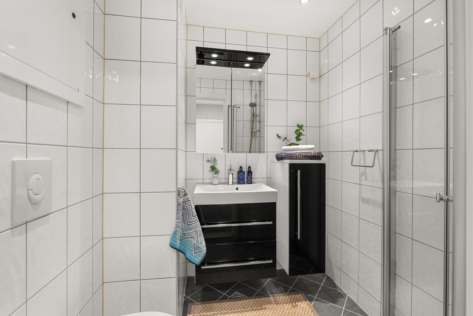 Fra entréen er det direkte adkomst til et pent flislagt baderom som ble pusset opp i regi av borettslaget i 2013. Baderommet har fliser på vegger og gulv, og varme i gulv og downlights i tak. Galleribilde