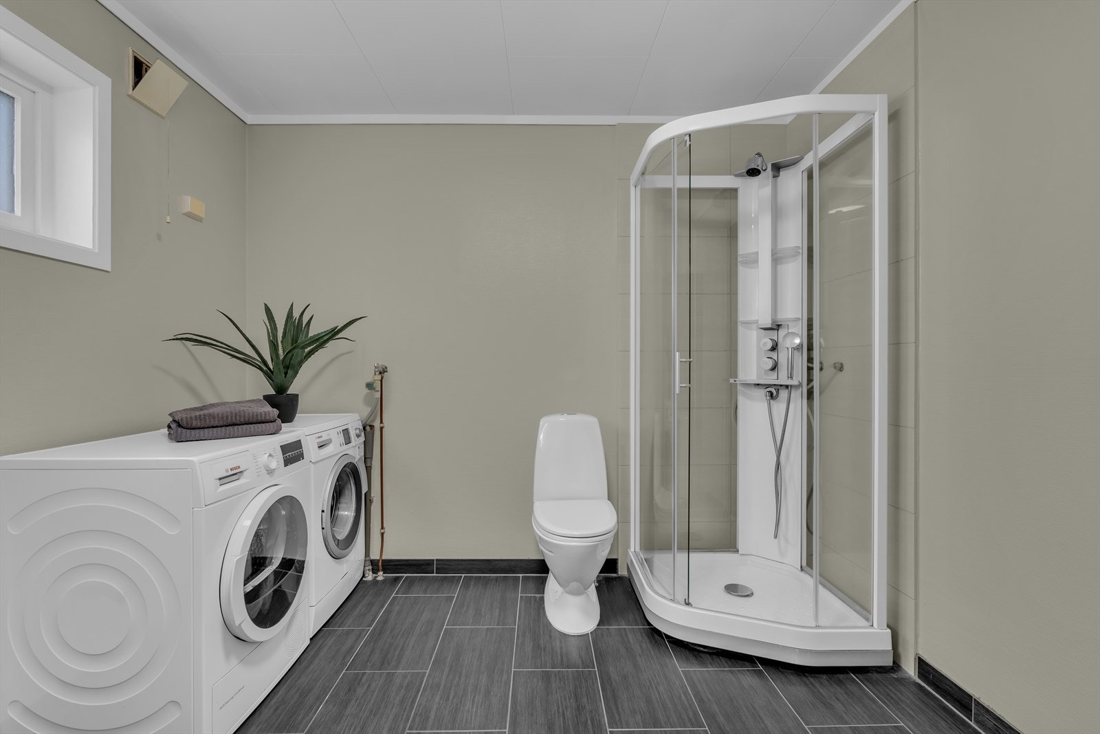 Badet inneholder et toalett og et dusjkabinett. Det er også opplegg for både vaskemaskin og tørketrommel Galleribilde