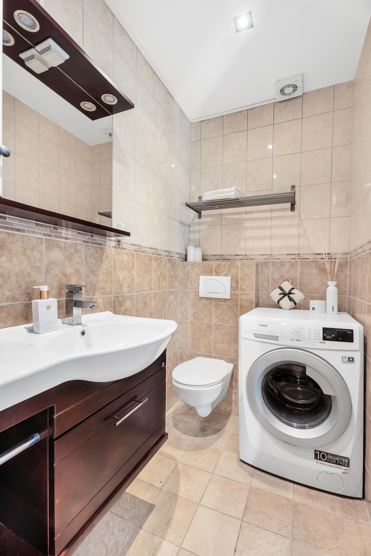 Badet inneholder dusjnisje med skyvedører, vegghengt toalett og innredning med nedsunket servant med speil. Det er opplegg for vaskemaskin. Galleribilde