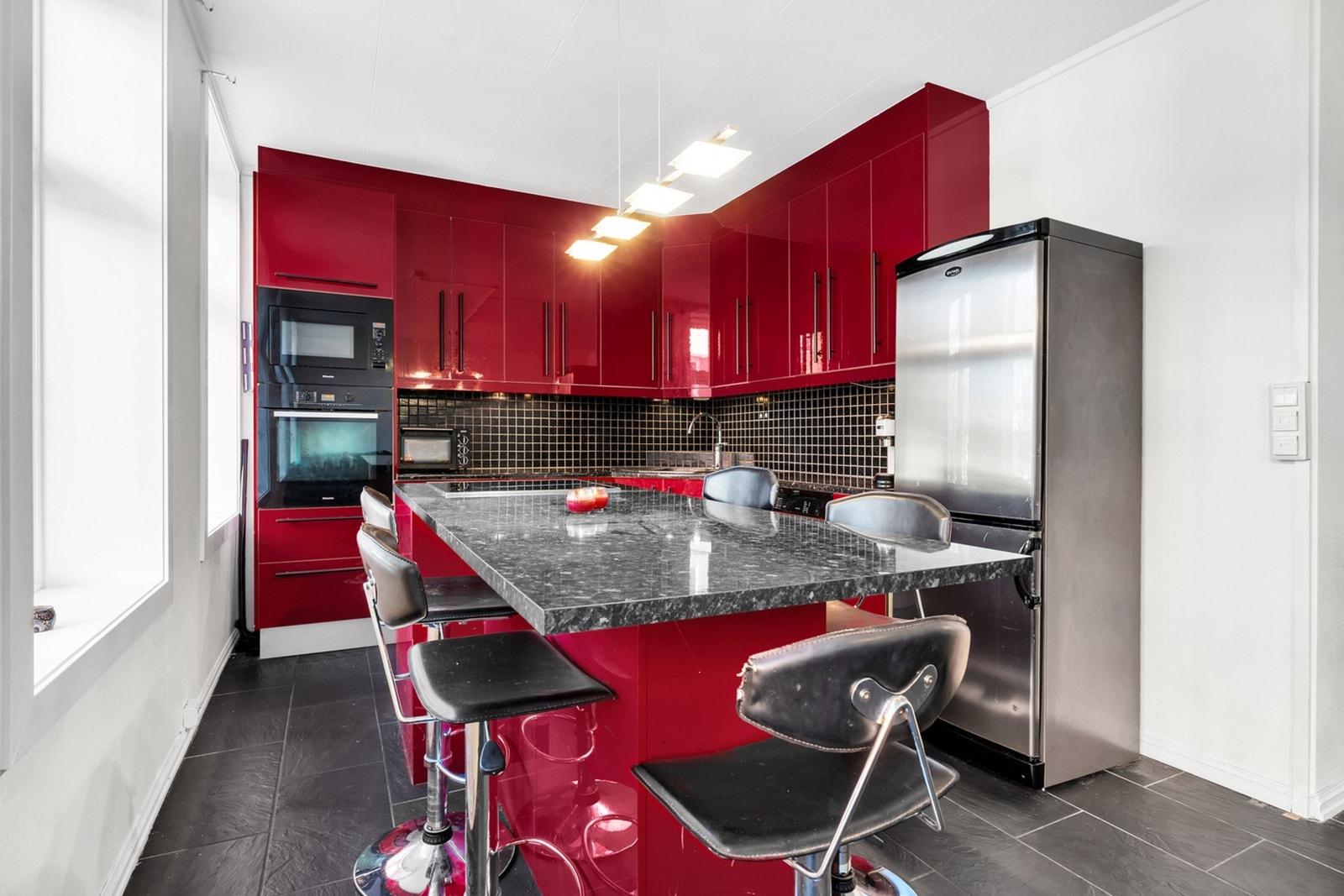 Kjøkkenøyen skaper en praktisk løsning med ekstra benkeplass, ideell for både matlaging og servering. Galleribilde