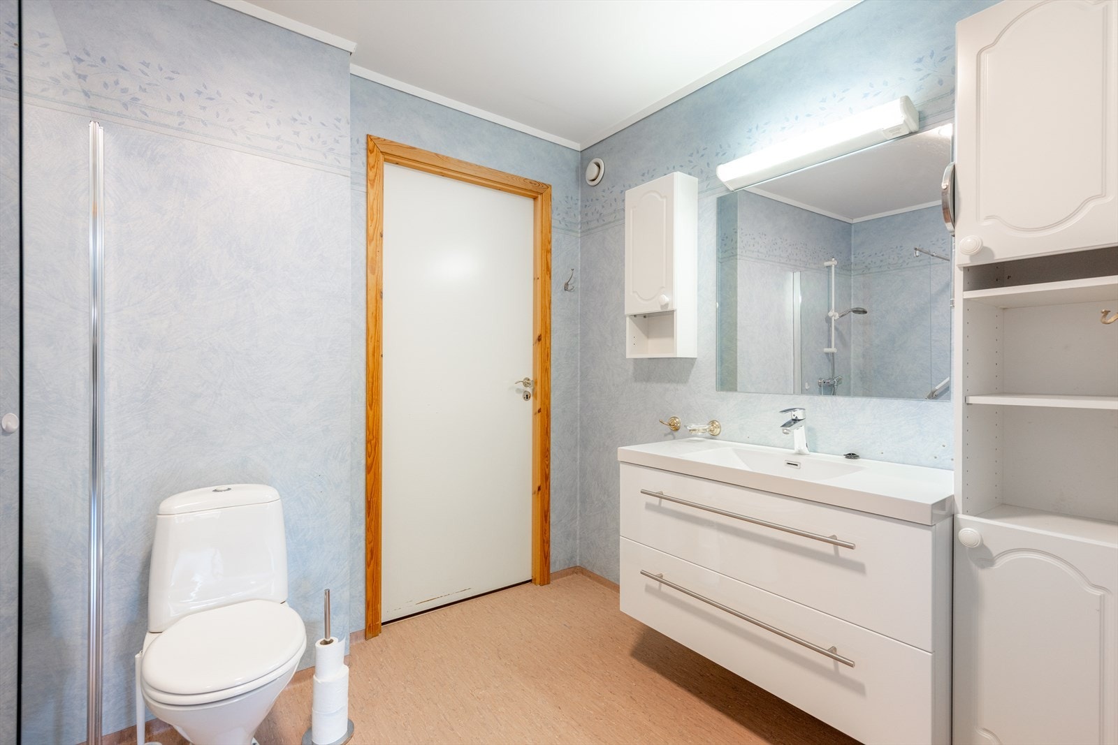 Badet har varmekabler i gulv, gulvmontert toalett og nyere servantinnredning med skuffer og heldekkende servant. Galleribilde