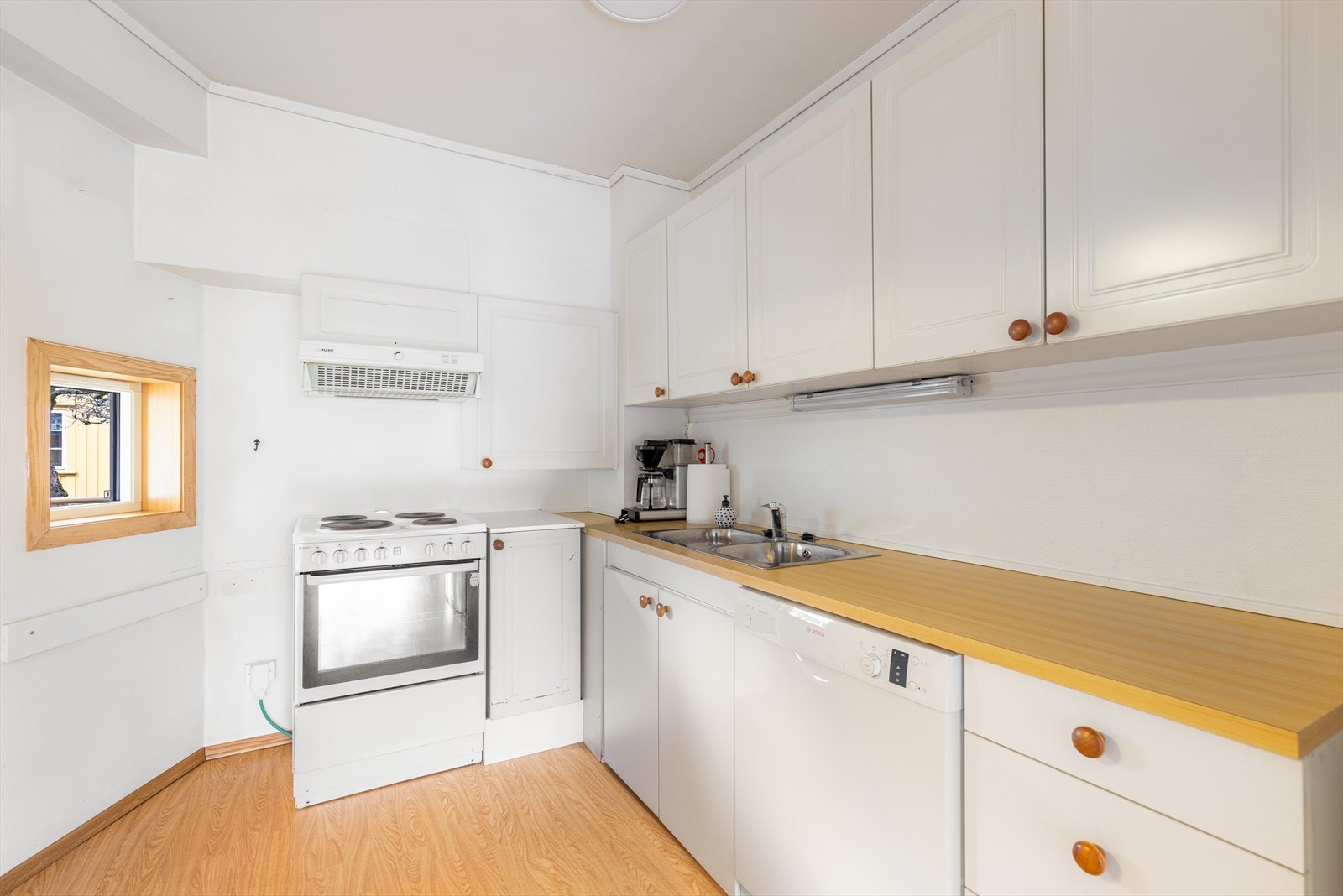 Lys kjøkkeninnredning fra byggeår, med fabrikkmalte fronter i profilert utførelse og laminert benkeplate med gode arbeidsflater. Galleribilde