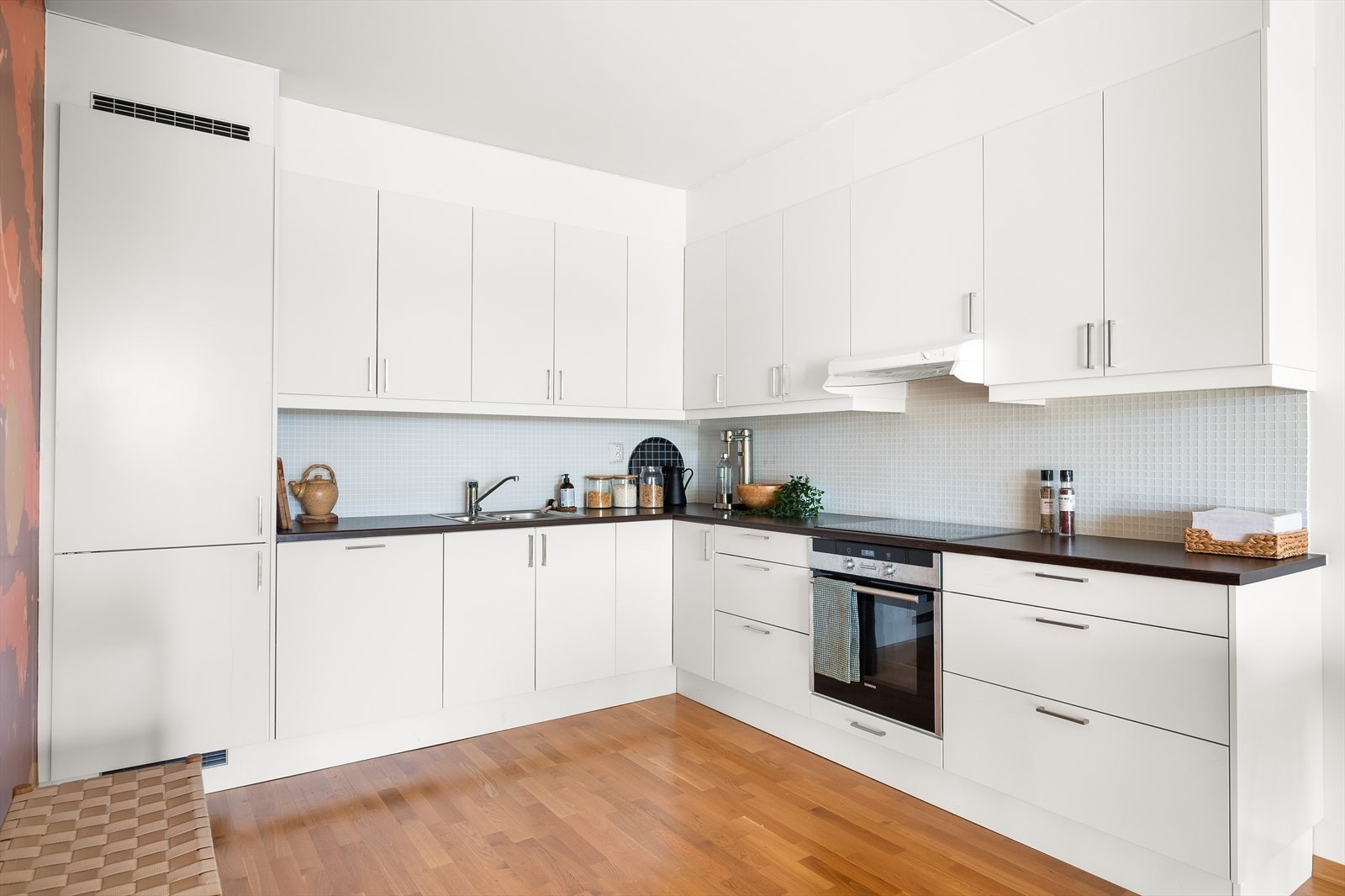 Pent og tidløst kjøkken med hvite glatte fronter og benkeplate av laminat. Galleribilde