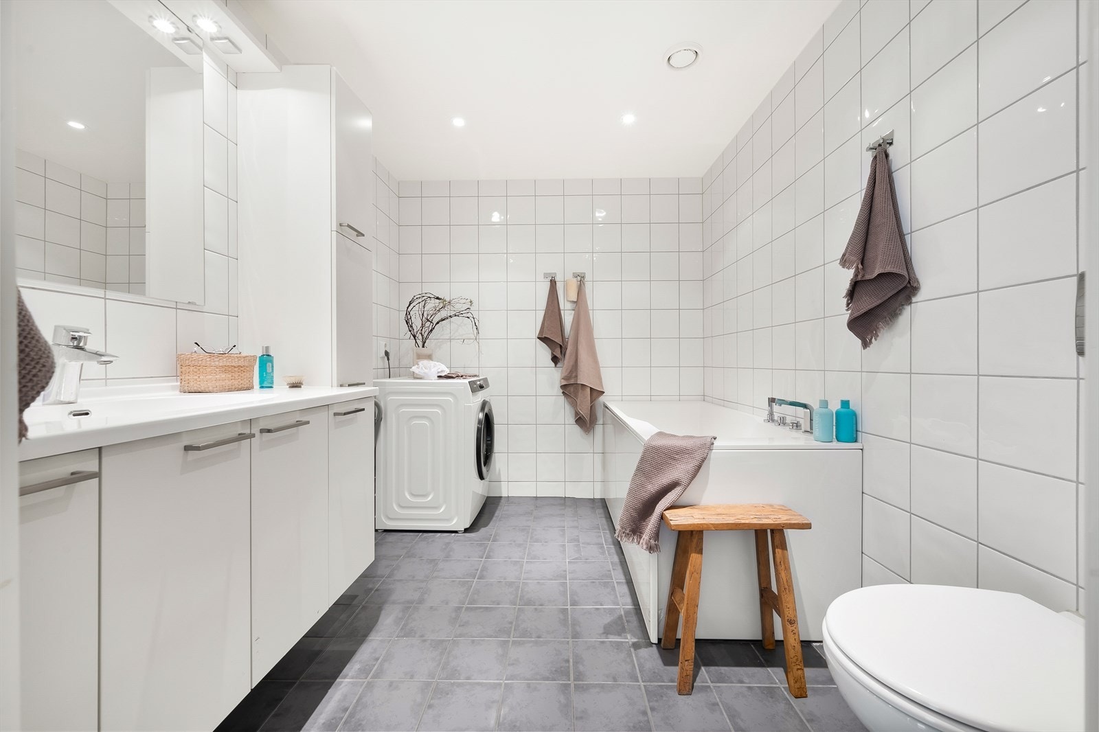 Det første badet er utstyrt med badekar og servant i skapseksjon med rikelig oppbevaringsplass. Det er vannklosett samt opplegg for vaskemaskin. Galleribilde