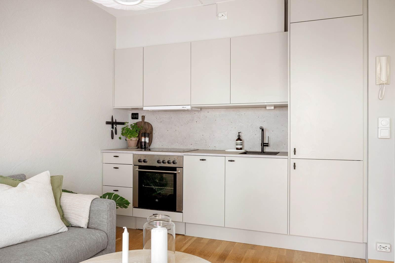 Et stilrent kjøkken med beige fronter og benkeplate i laminat med nedfelt kjøkkenkum i svart kompositt og et-greps blandebatteri. Galleribilde
