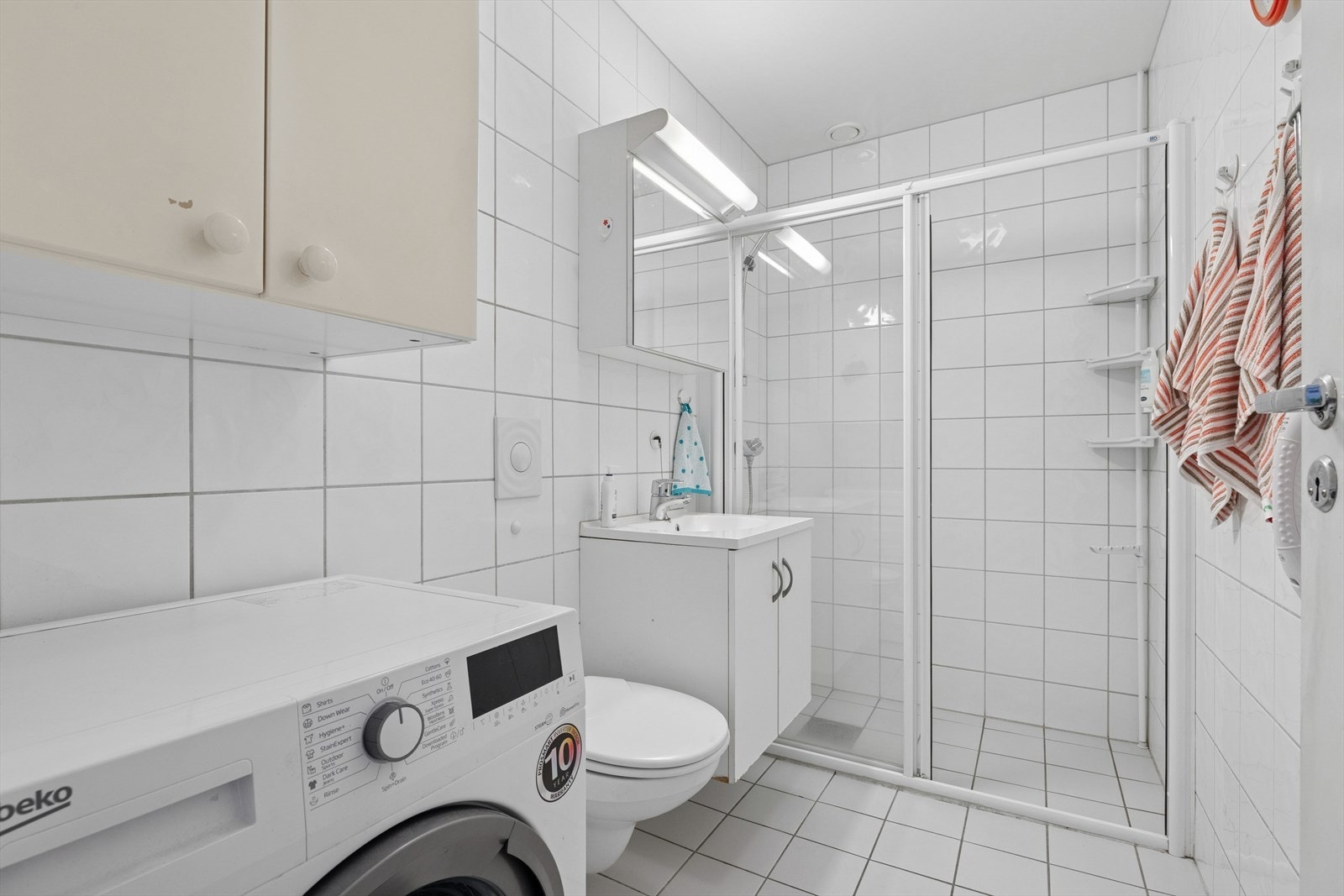 Badet er innredet med vegghengt toalett, romslig dusj, servant og opplegg for vaskemaskin. Galleribilde