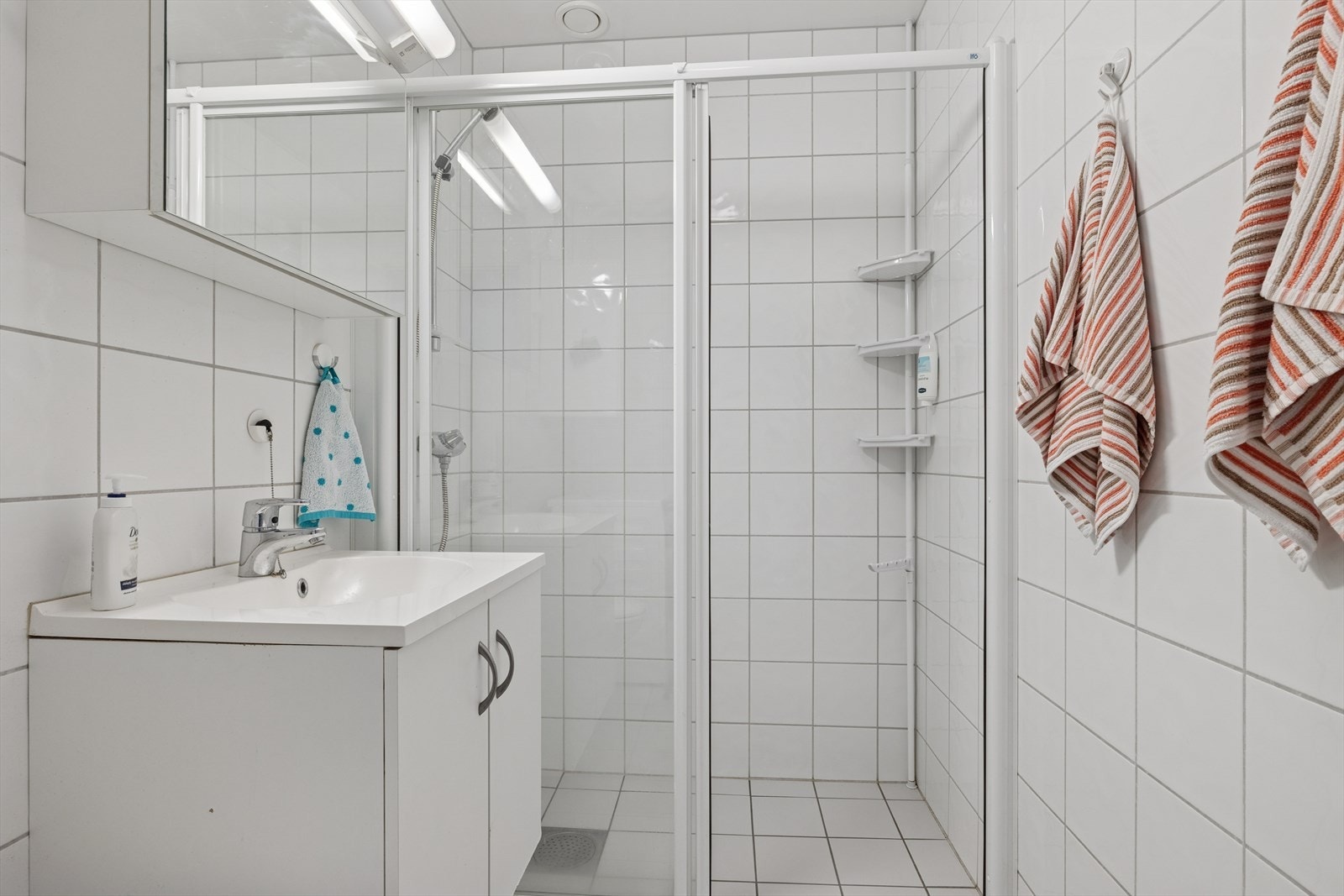 Badet er helfliset og har behagelig gulvvarme. Innredningen består av servant med heldekkende vask og har praktiske oppbevaringsmuligheter. Galleribilde