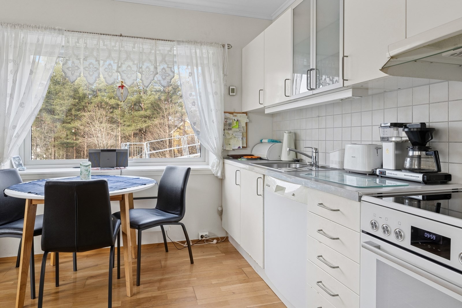 Mellom over- og underskapene finner du hvite fliser som gir et rent og klassisk uttrykk, og belysningen under overskapene gir et praktisk arbeidslys. Galleribilde