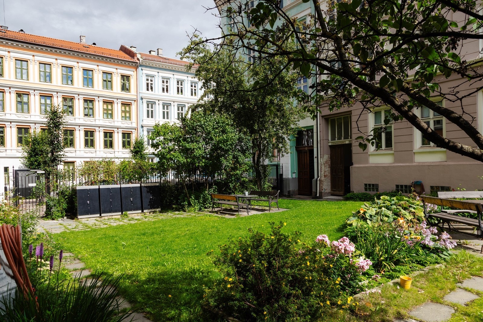 Om sommeren ser bakgården til borettslaget omtrent slik ut. Utrolig hyggelig uteplass med gressplen, beplantning og utemøbler. Galleribilde