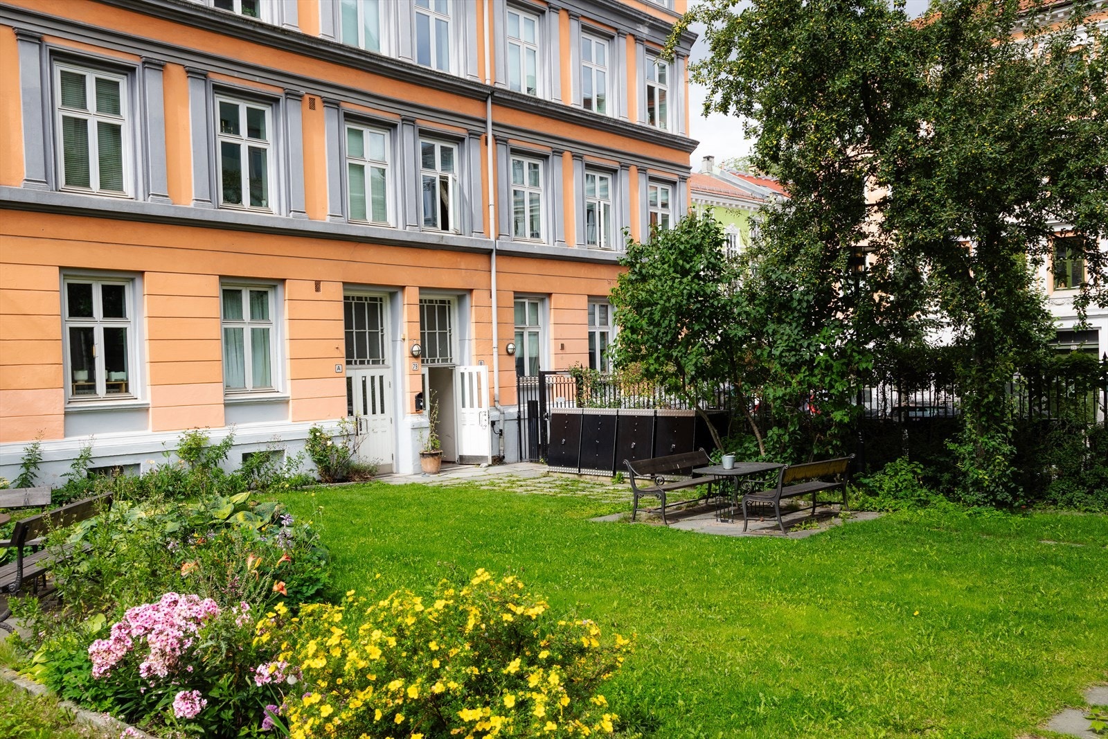 Om sommeren ser bakgården til borettslaget omtrent slik ut. Utrolig hyggelig uteplass med gressplen, beplantning og utemøbler. Galleribilde