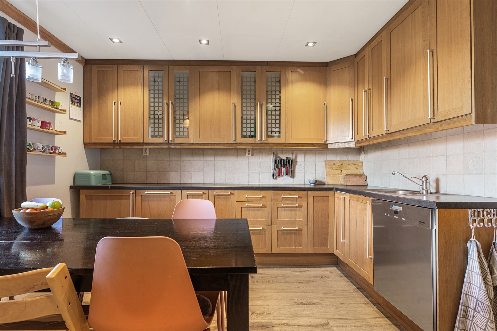 Kjøkkeninnredningen har profilerte skapfronter, laminat benkeplate og hvitevarer som oppvaskmaskin, kjøleskap/fryser og komfyr Galleribilde