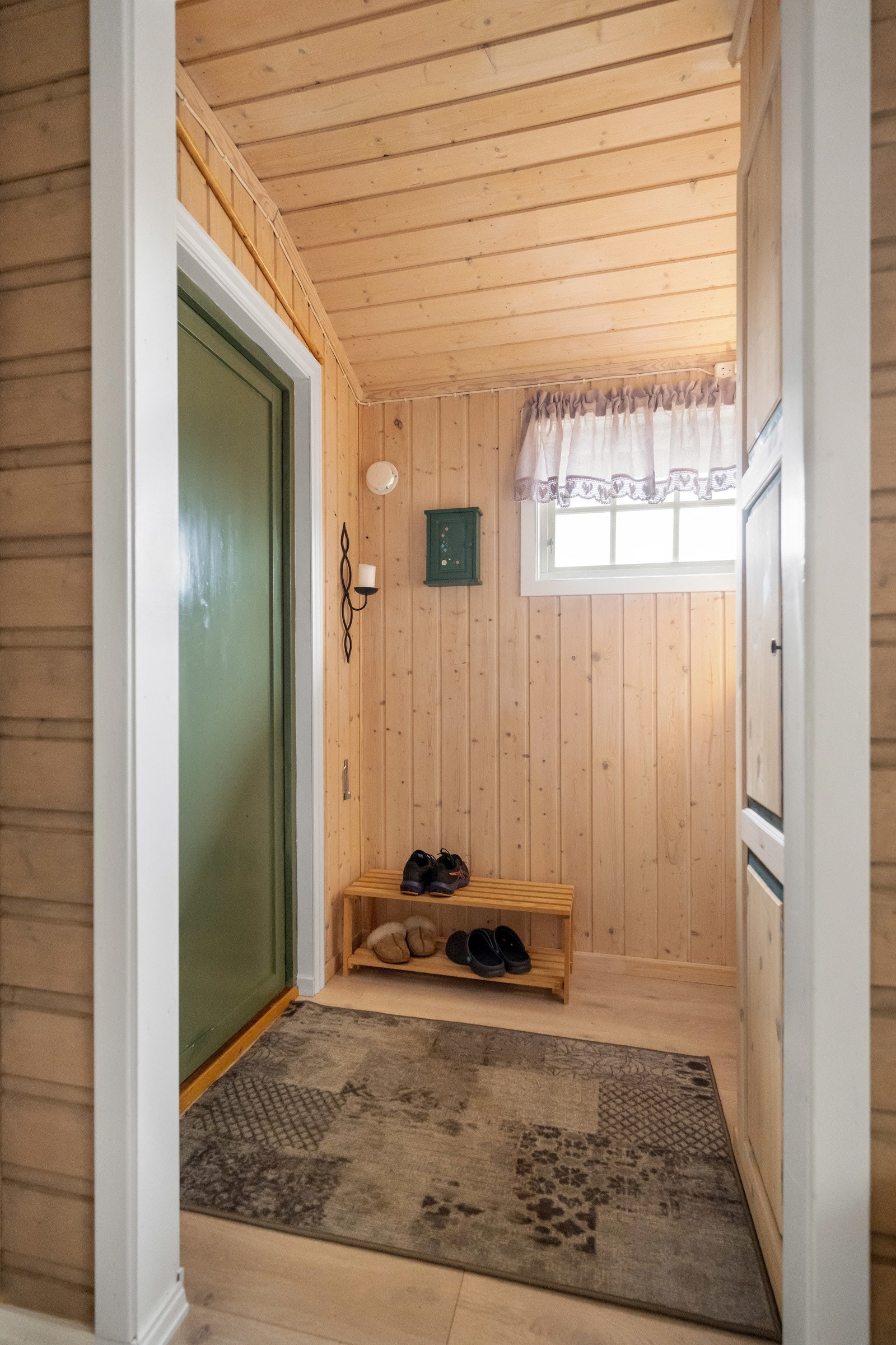 Gang med laminatgulv, malt panel på vegger og panel i himling. Plass til klær og sko i innebygd skap. Galleribilde