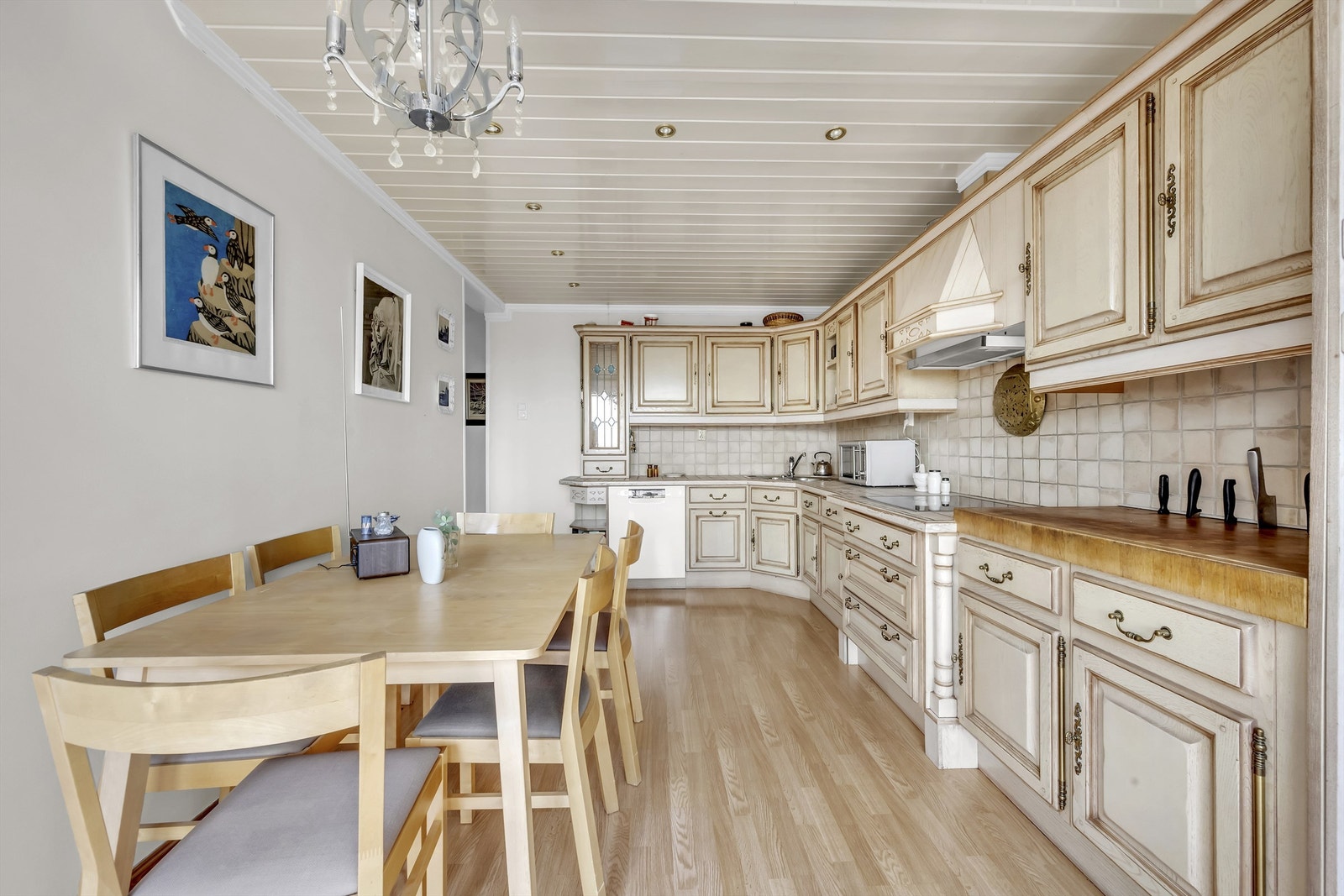 Kjøkkenet har profilerte fronter på skap og skuffer, benkeplate av fliser med nedfelt oppvaskkum og veggfliser mellom benkeplate og overskap Galleribilde