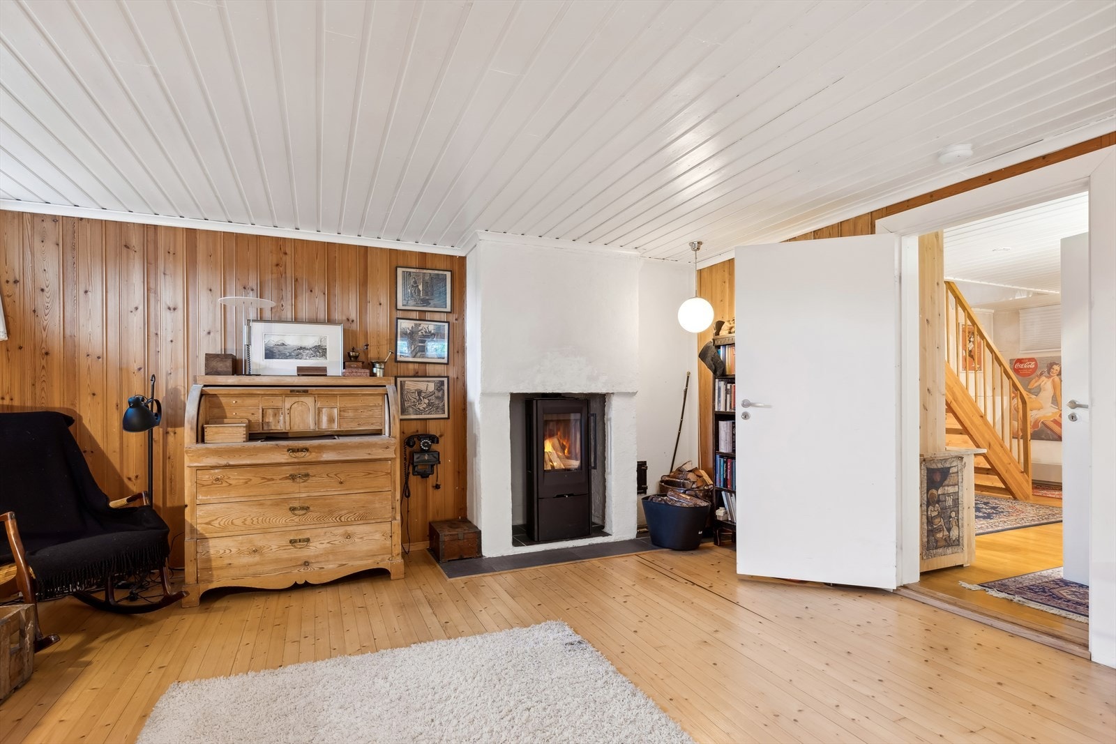 Kjellerstue med peisovn, tregulv og lysmalt panel i himling. Galleribilde