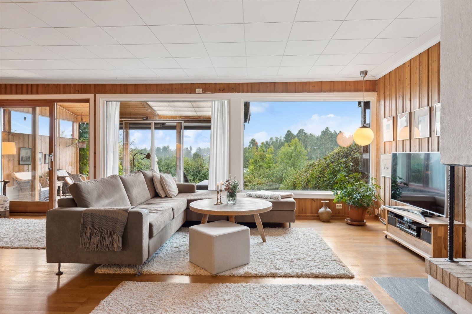 Stor og lys stue med parkett, panel og plater i himling. Galleribilde