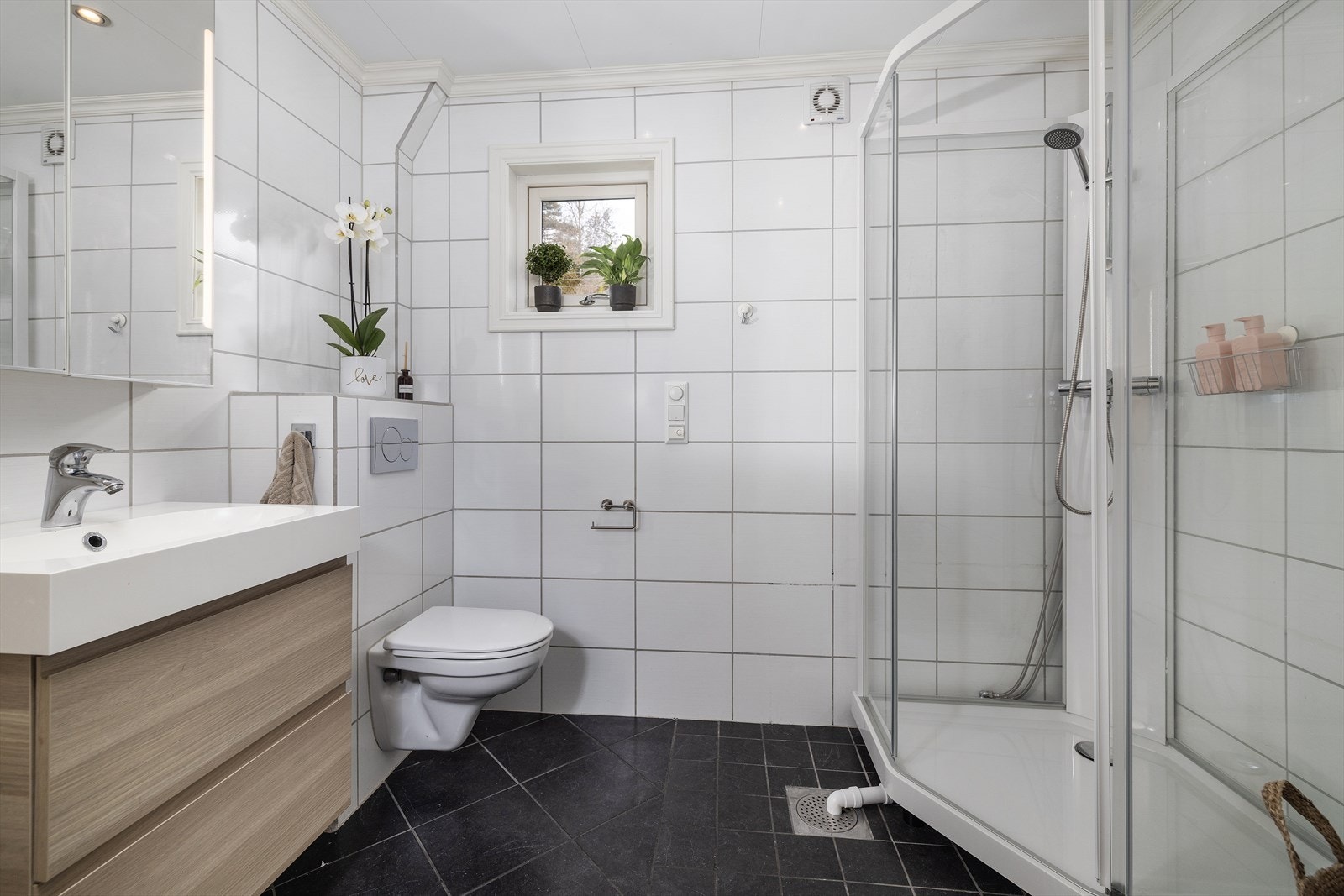 Badet i første etasje ble etablert i 2011 og fremstår lyst og innbydende. Rommet er utstyrt med innredning som inkluderer en nedfelt servant, veggskap med speil, veggmontert toalett og dusjkabinett. Galleribilde