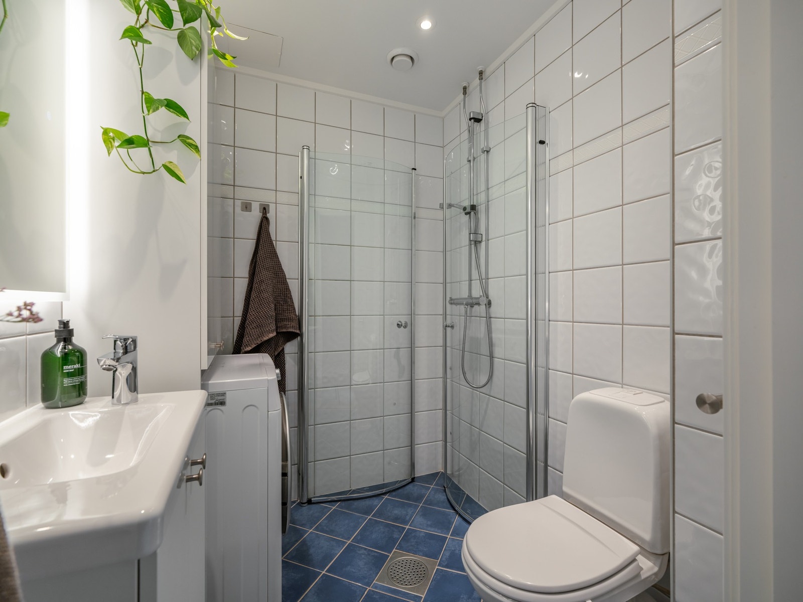 Badet er innredet med dusjhjørne, toalett, servant med skapinnredning og høyskap. Galleribilde