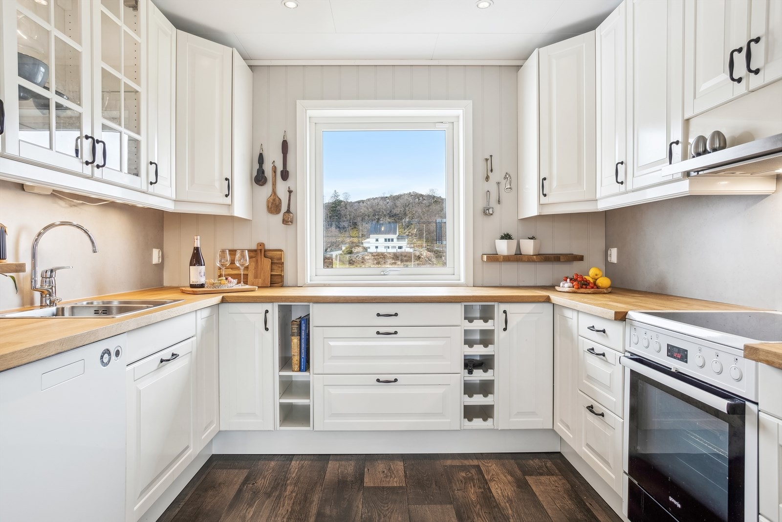 Kjøkkenet er innredet med hvite, profilerte fronter Galleribilde