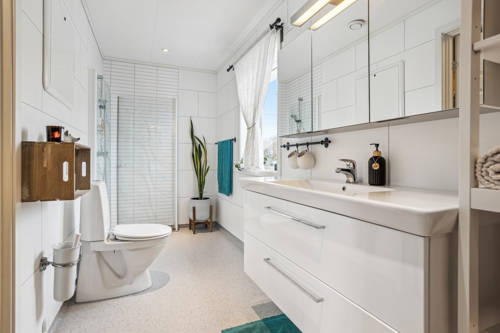 Lyst og romslig bad, innredet med tidløs innredning. Våtromsbelegg på gulv med elektriske varmekabler. Galleribilde