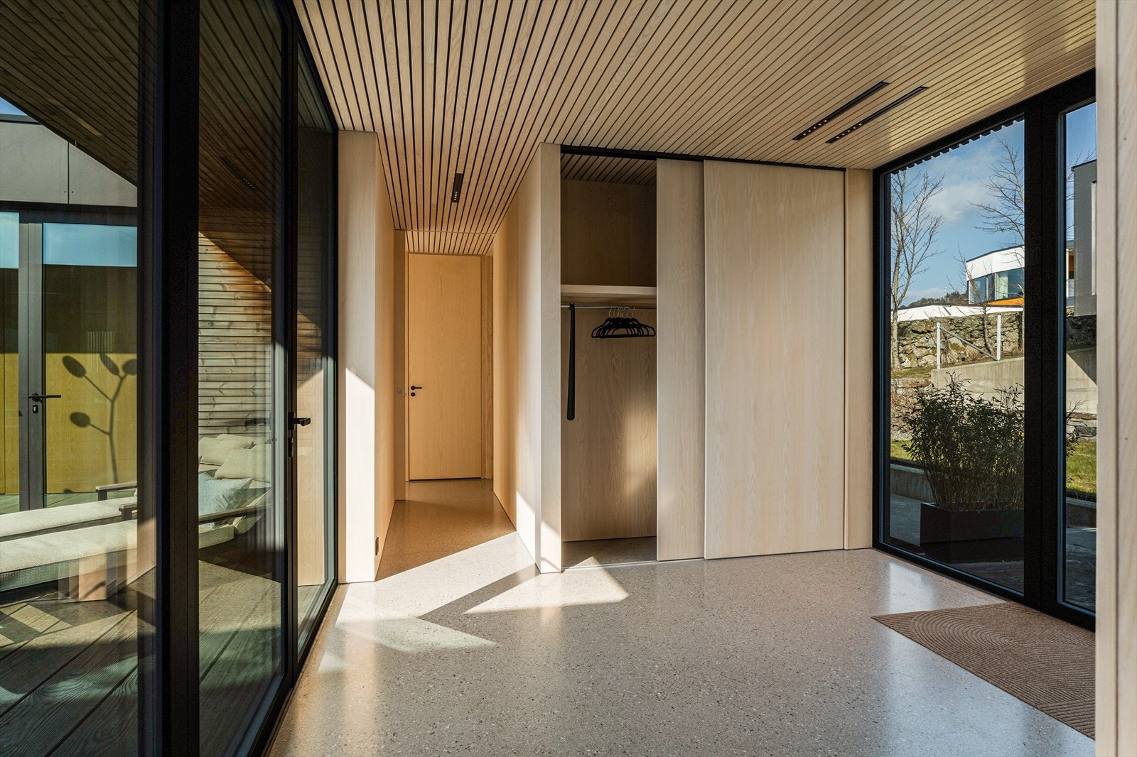 Hall med garderobe og adkomst inn mot soveromsfløy. Alt av vegger, tak og plassbygget garderobe er levert i heltre ask Galleribilde