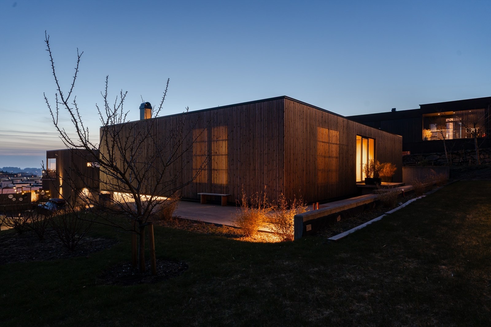 Boligens fasade er kledd med malmfurukledning og vinduene er skjermet bak. Fra innsiden ser du ut mens innsynet er svært begrenset. Galleribilde