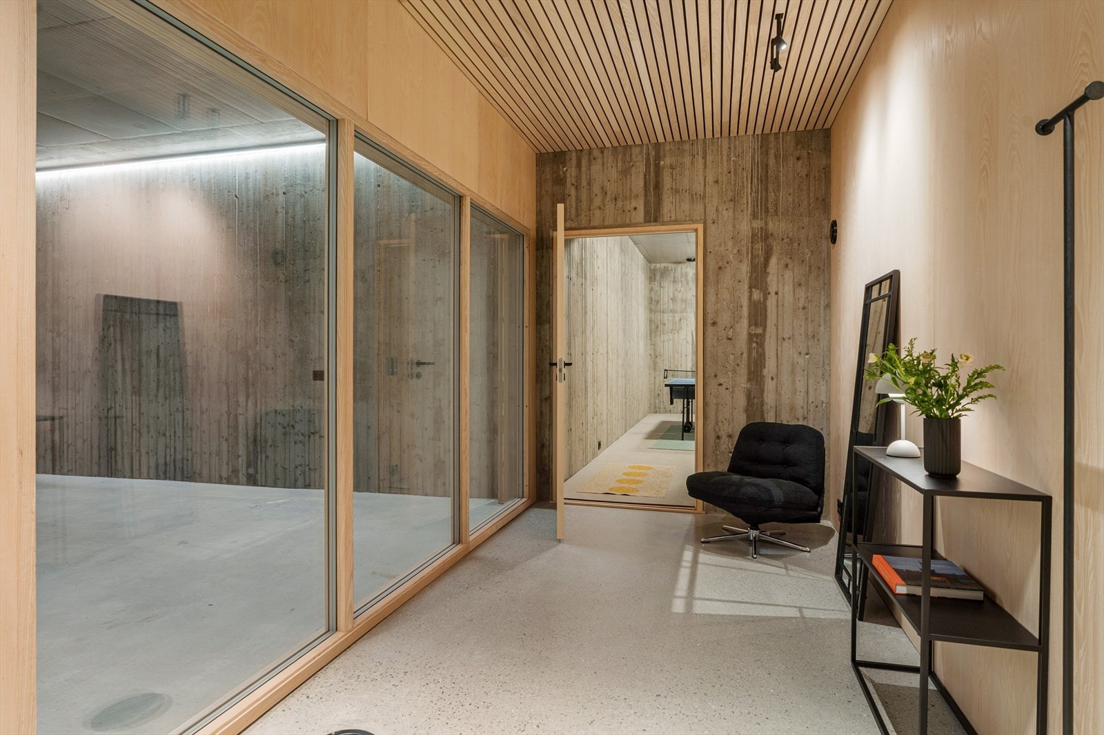 Kjelleren er lys og trivelig og er innredet med det samme betonggulvet og inngang til garasje og trimrom Galleribilde