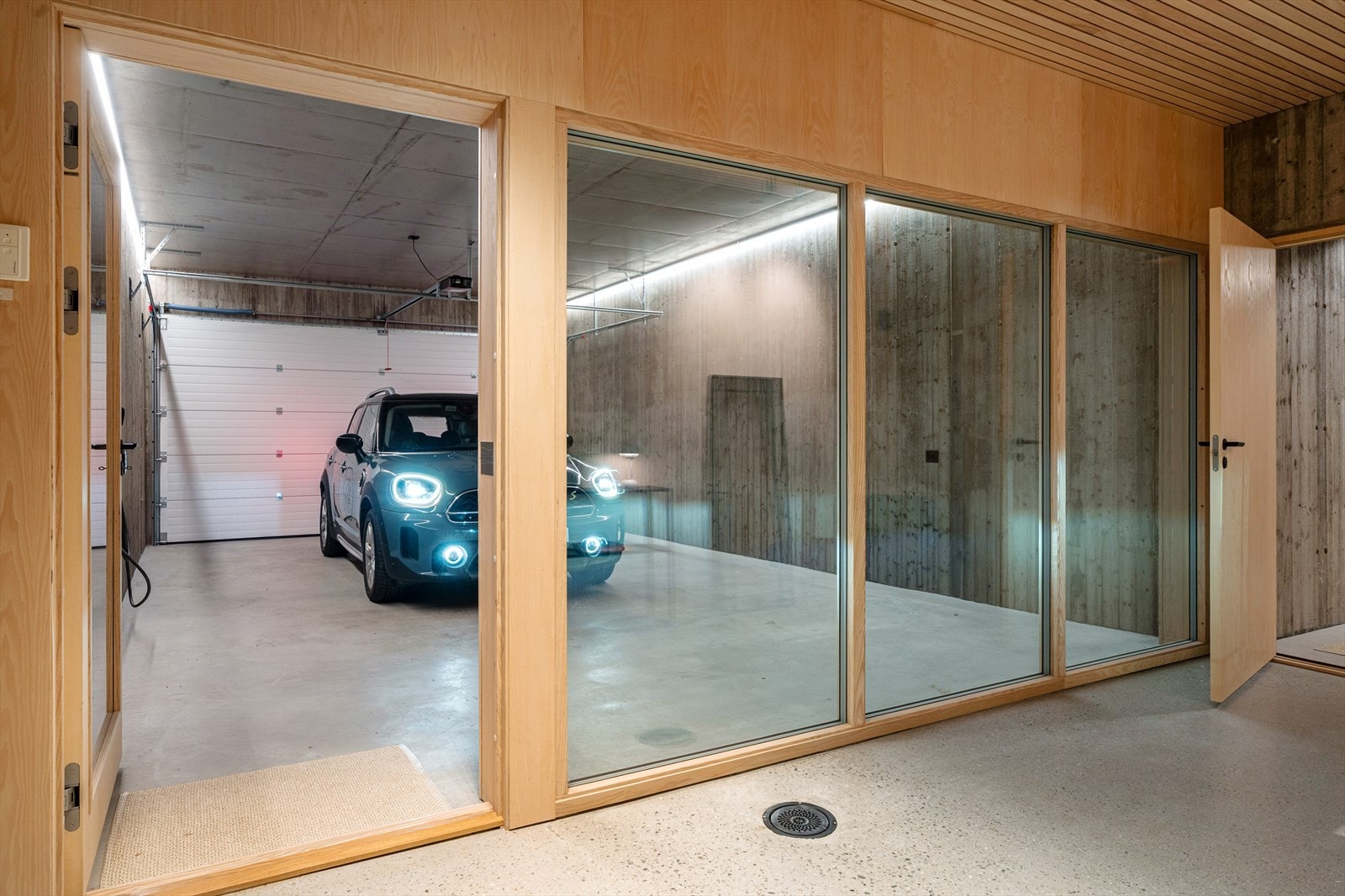 Oversiktlig garasje med glassvegg inn mot gang Galleribilde