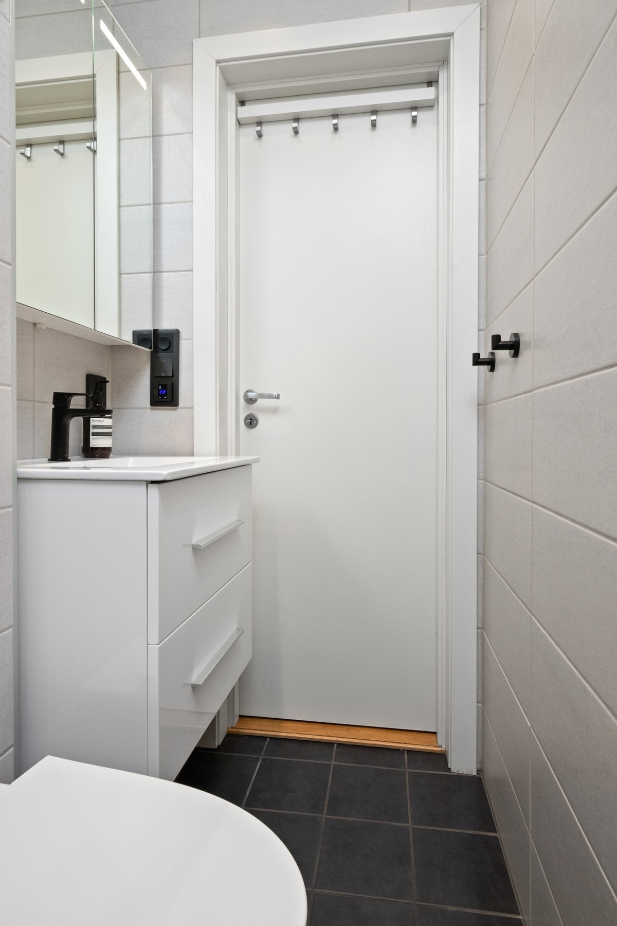 Badet er utført med mørke gulvfliser, lyse veggfliser, gulvvarme og downlights. Galleribilde